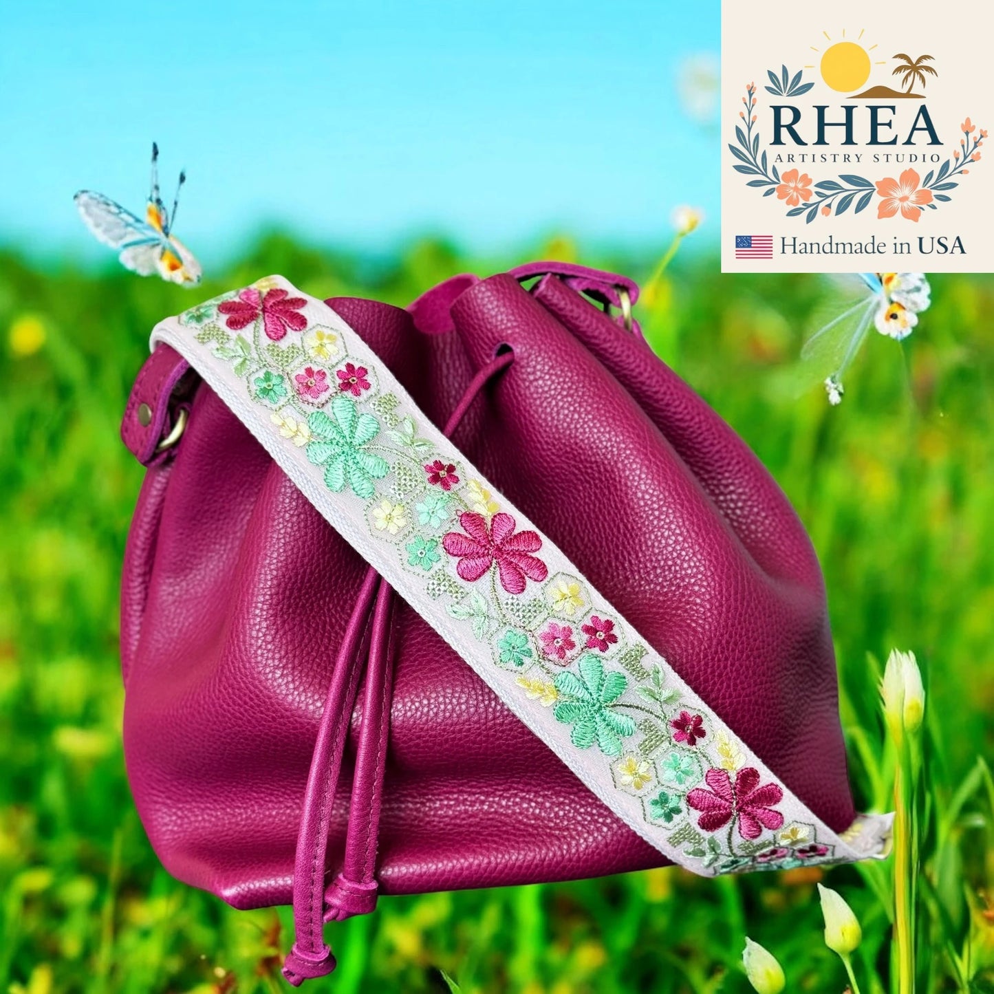 Purple leather bag with floral strap on a grassy background, featuring the RHEA Artistry Studio logo.