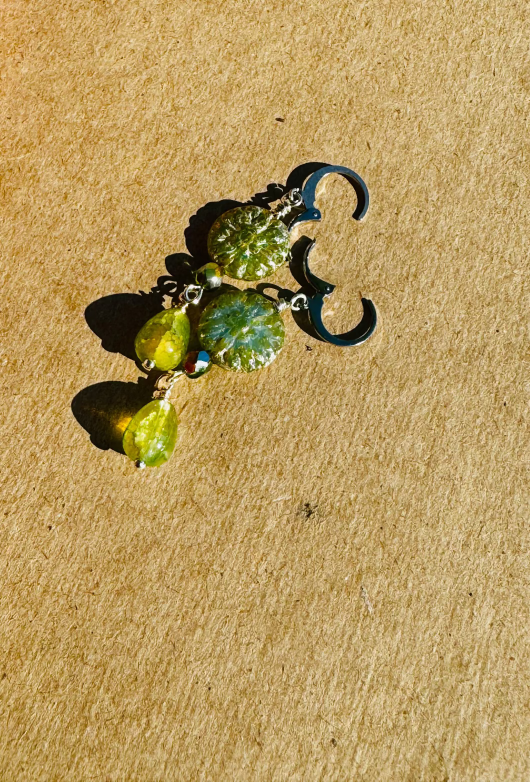 Gold earrings with green stones on old book