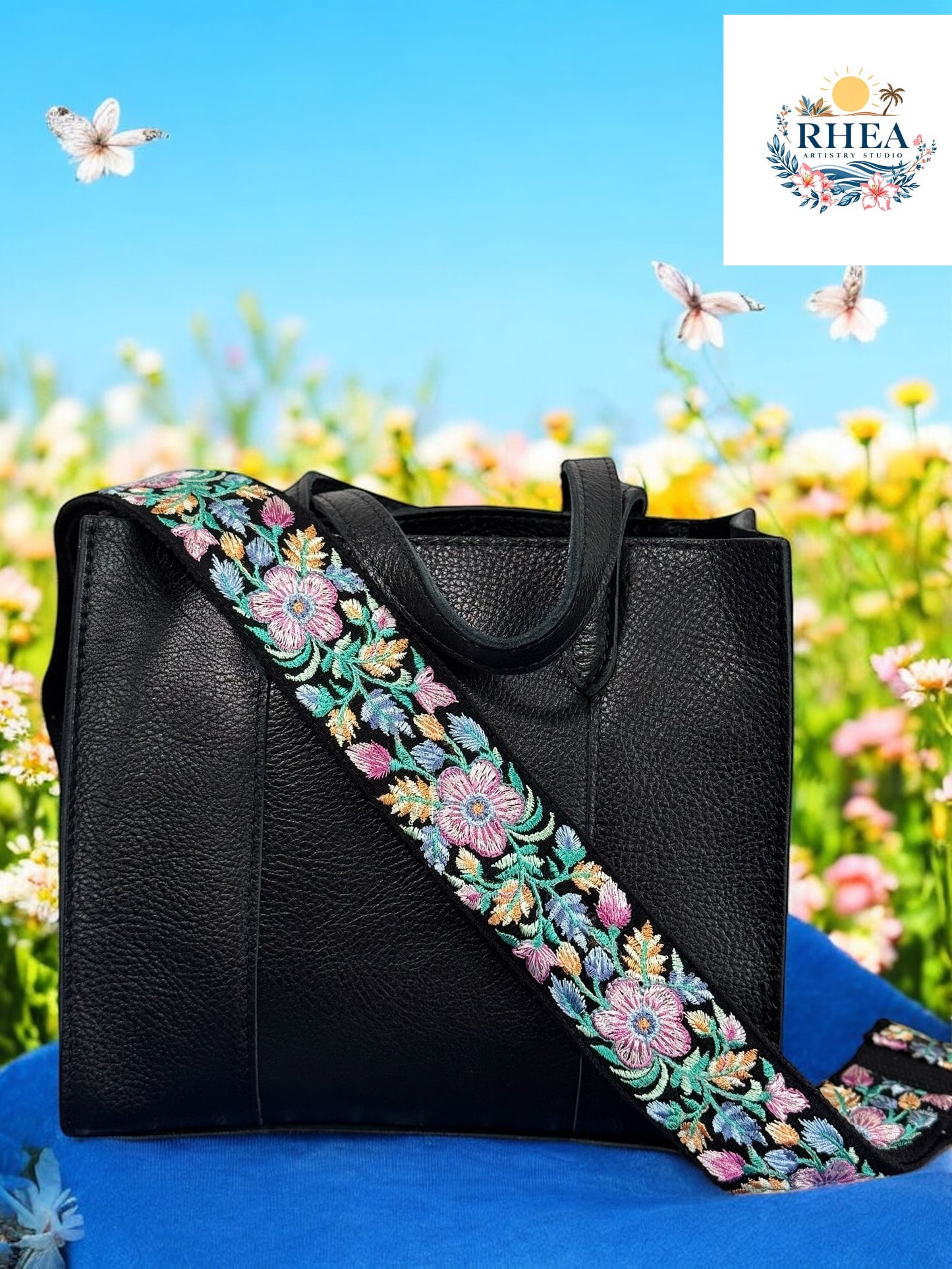 A black purse with a floral embroidered purse strap set against a field of colorful flowers.