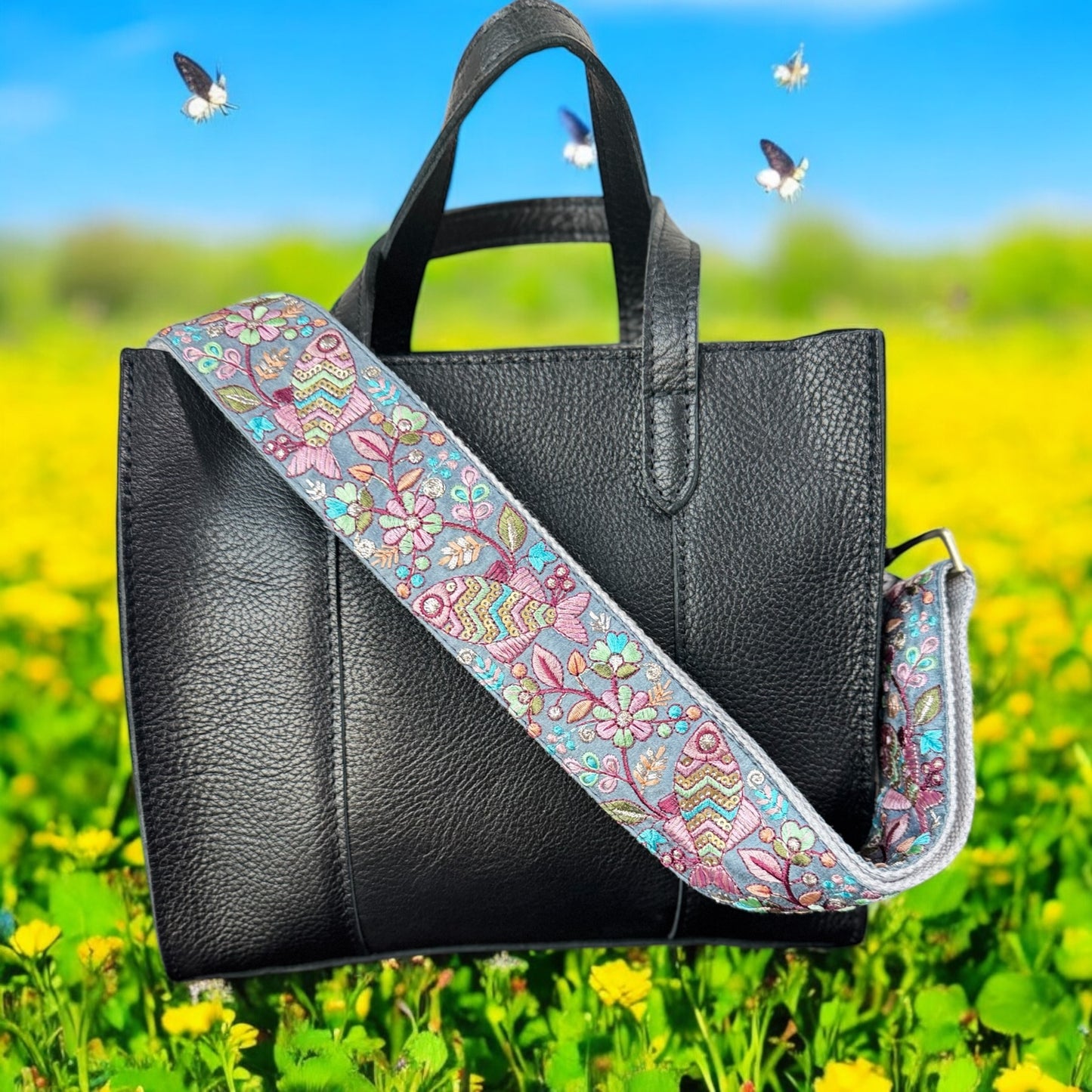 Adjustable embroidered purse strap with floral patterns and gold hardware, displayed on a gray background.