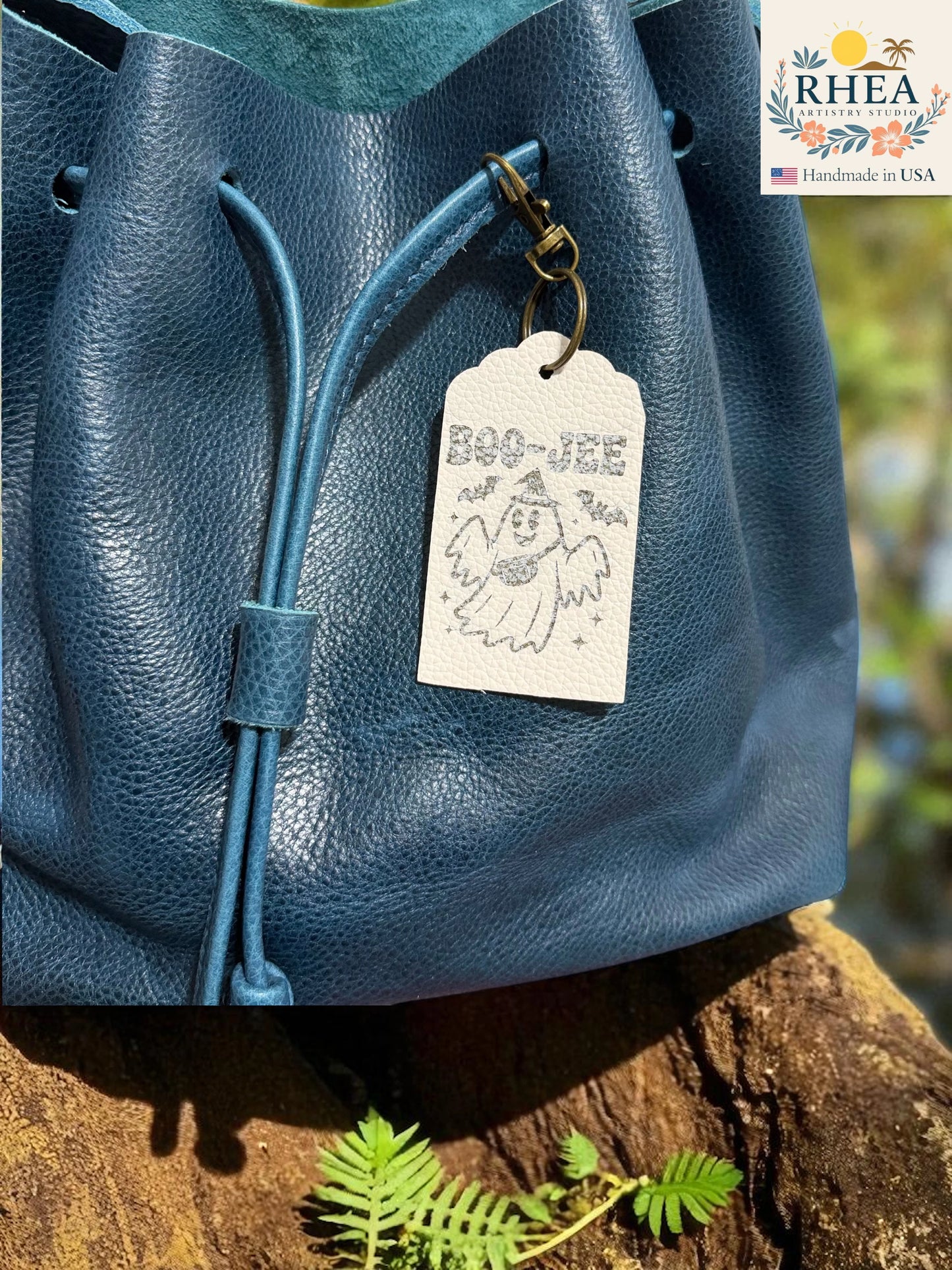 Blue leather bag with a tag on a wooden surface, featuring the RHEEA brand.
