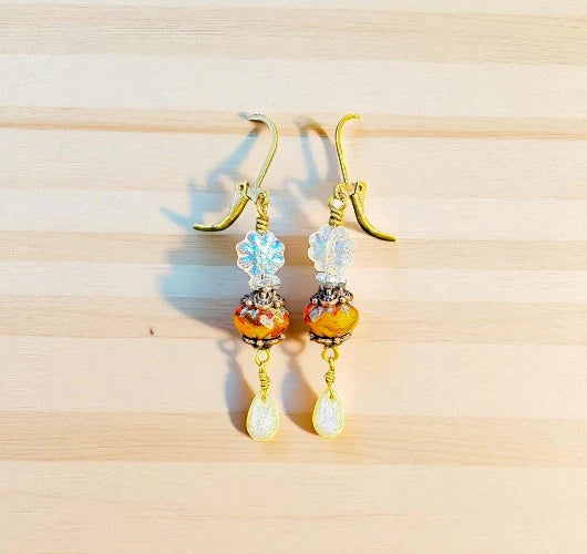 Pair of earrings with colorful beads on a wooden surface
