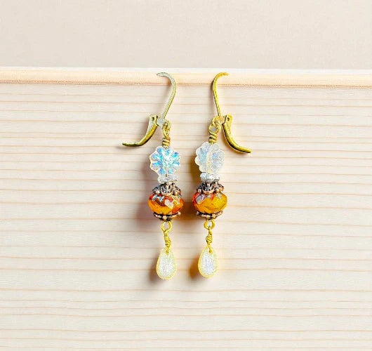 Pair of earrings with colorful beads on a light wooden surface