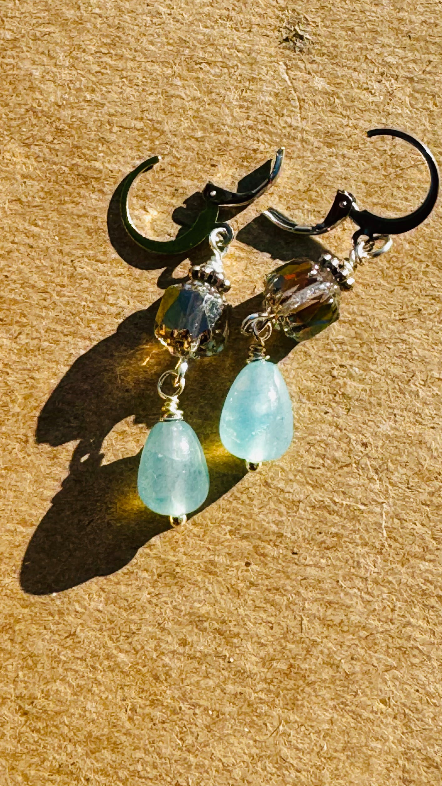A pair of cathedral-shaped silver drop earrings with light blue colored glass.