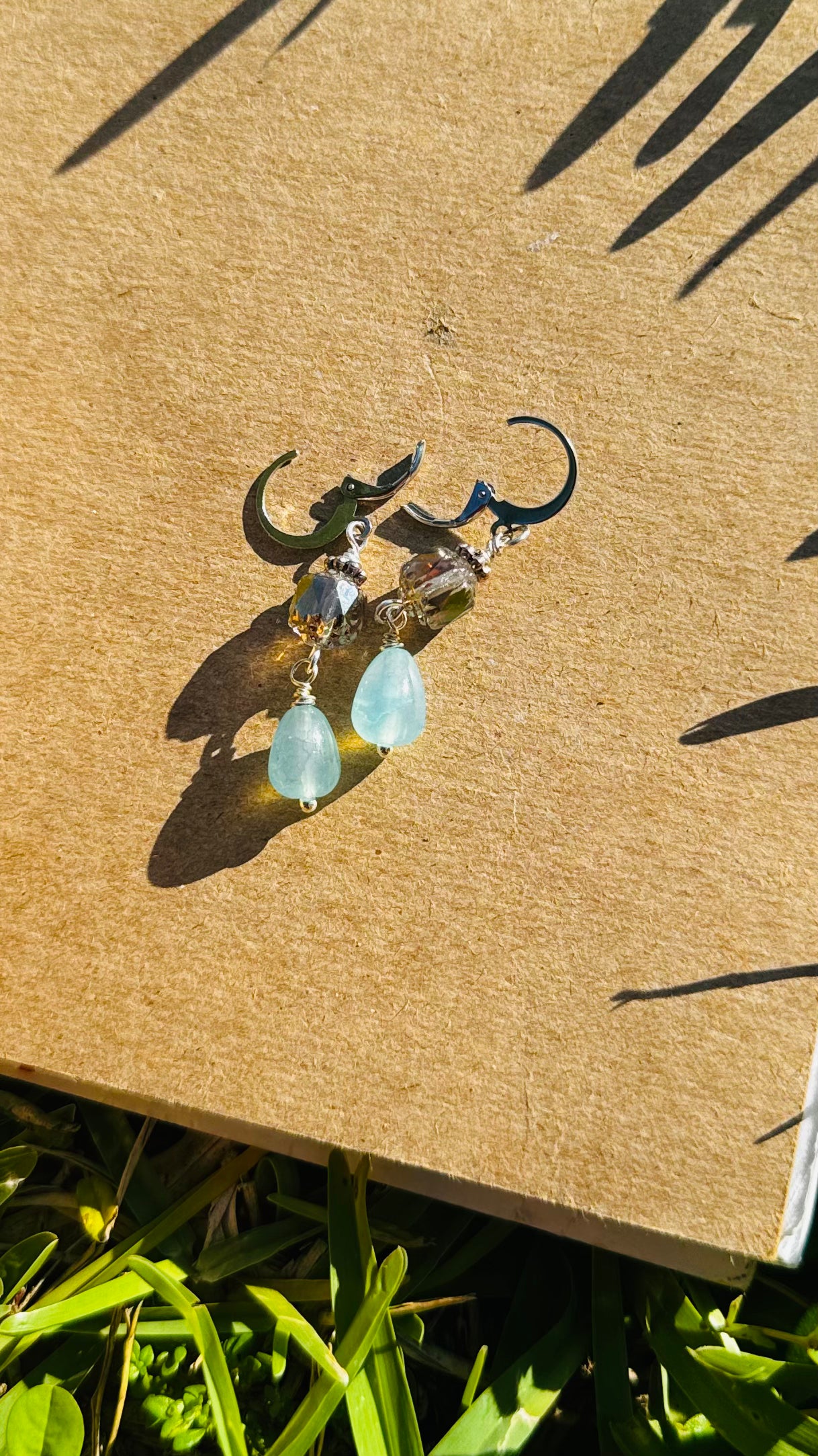 A pair of cathedral-shaped silver drop earrings with light blue colored glass.