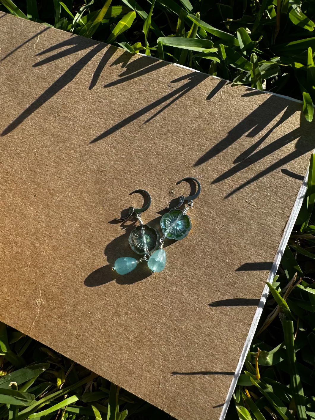 A pair of cathedral-shaped silver drop earrings with light blue colored glass.