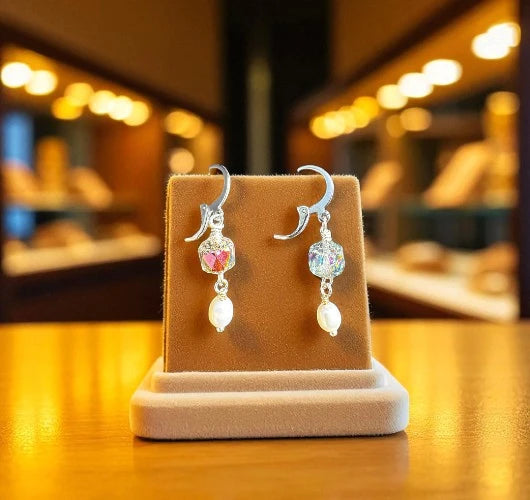 Pair of earrings on a brown display stand with a blurred background