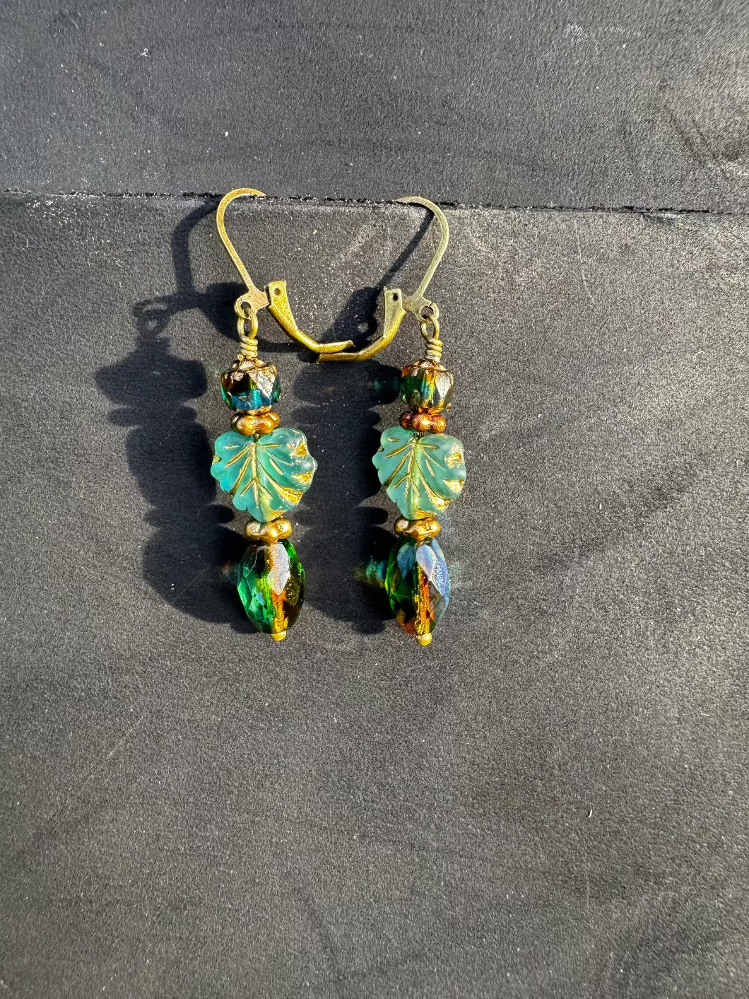 Handmade Czech glass earrings with celestial glow. Perfect for adding elegance to any outfit. Green drop ,leaf and cathedral bead