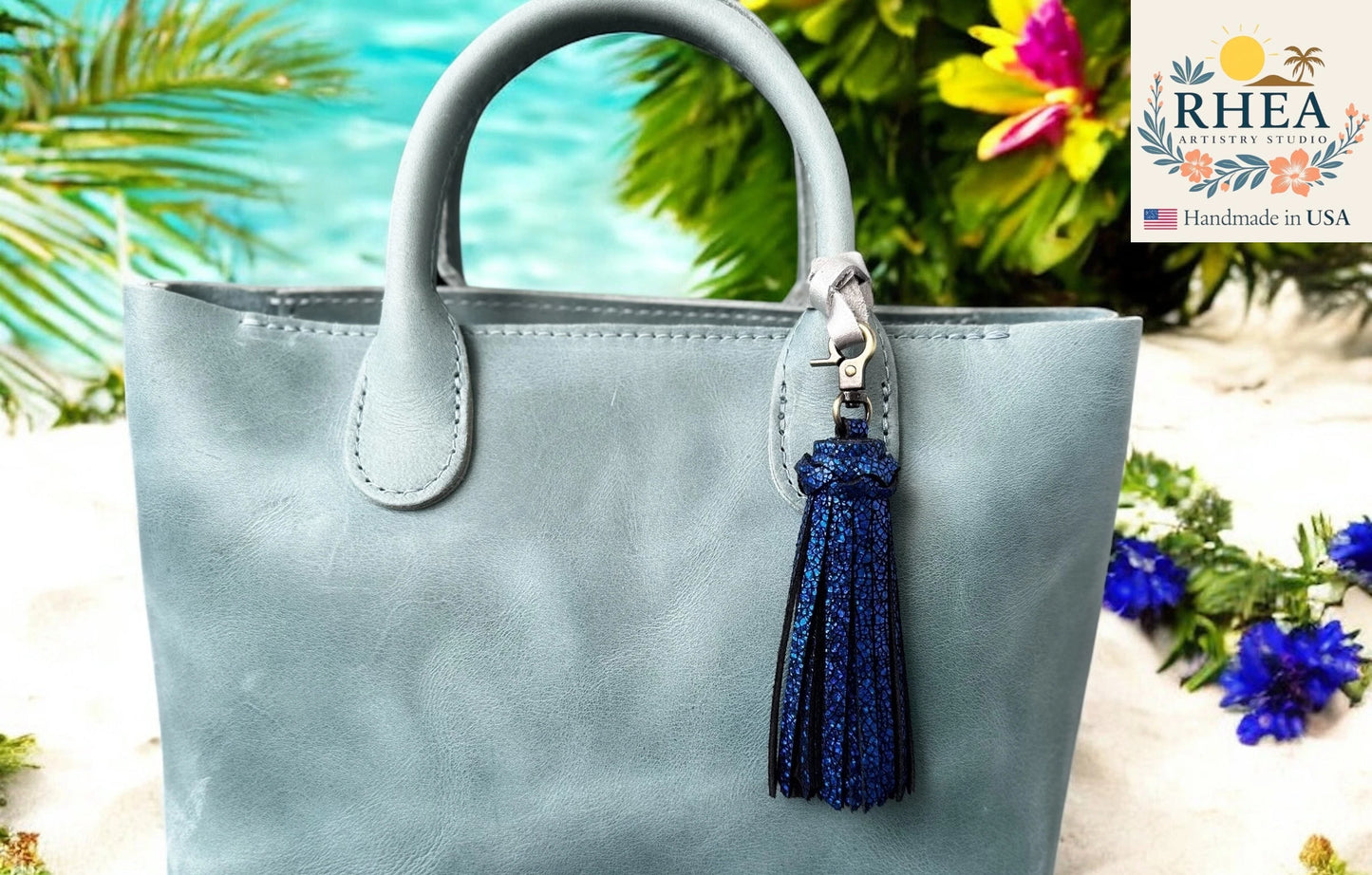 Light blue handbag with a blue tassel keychain against a blurred natural background
