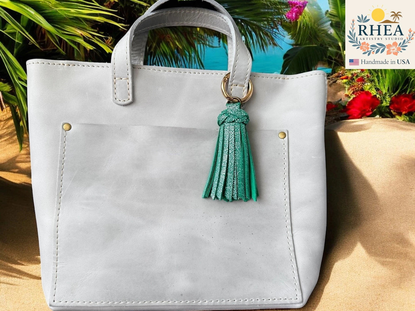 White handbag with a green tassel against a tropical background