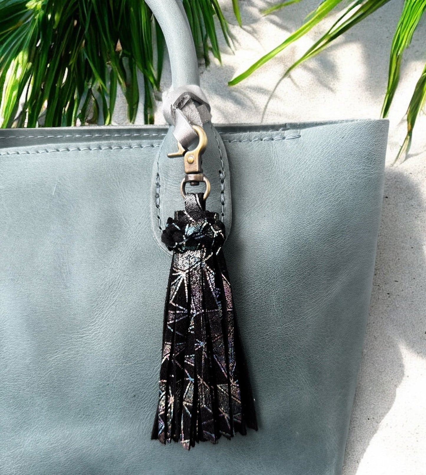 Tassel keychain attached to a light blue bag with a plant in the background