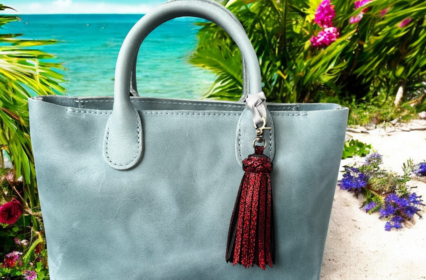 Light blue handbag with a red tassel against a beach background