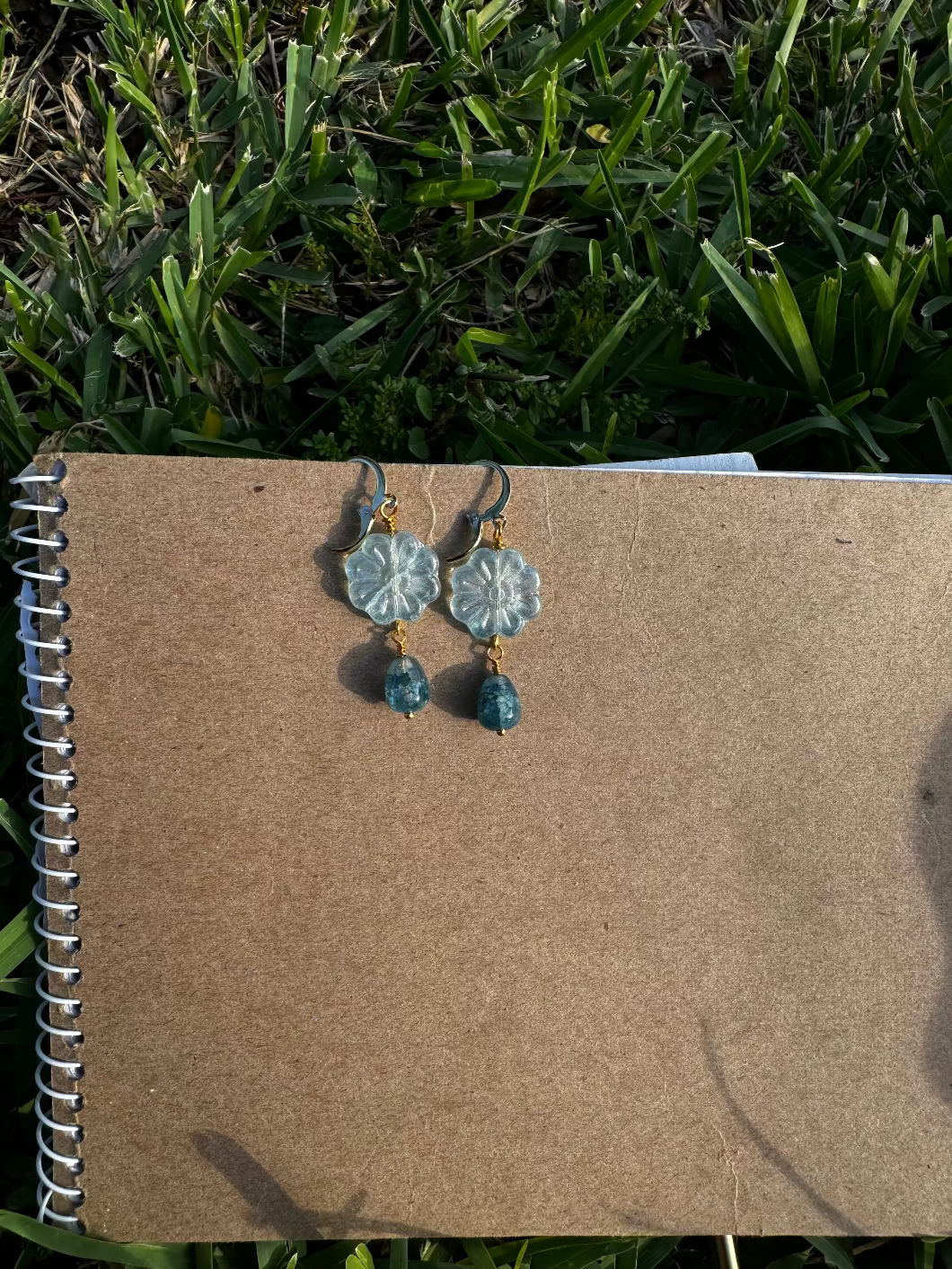 Floral earrings with blue beads on an old book