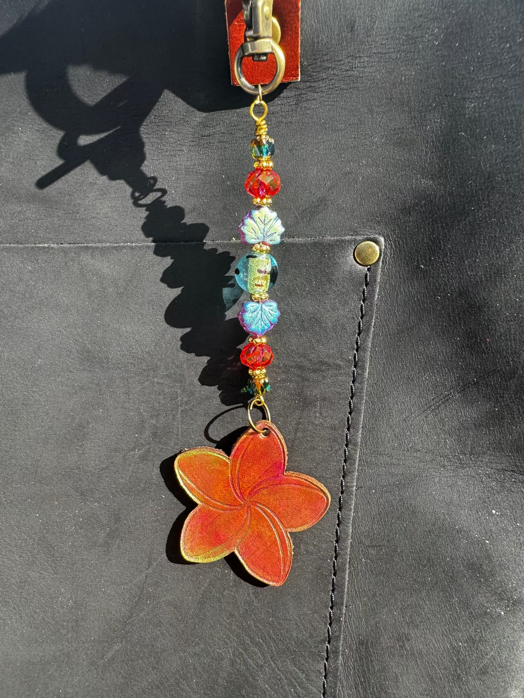 Flower-shaped keychain with beads on a black bag
