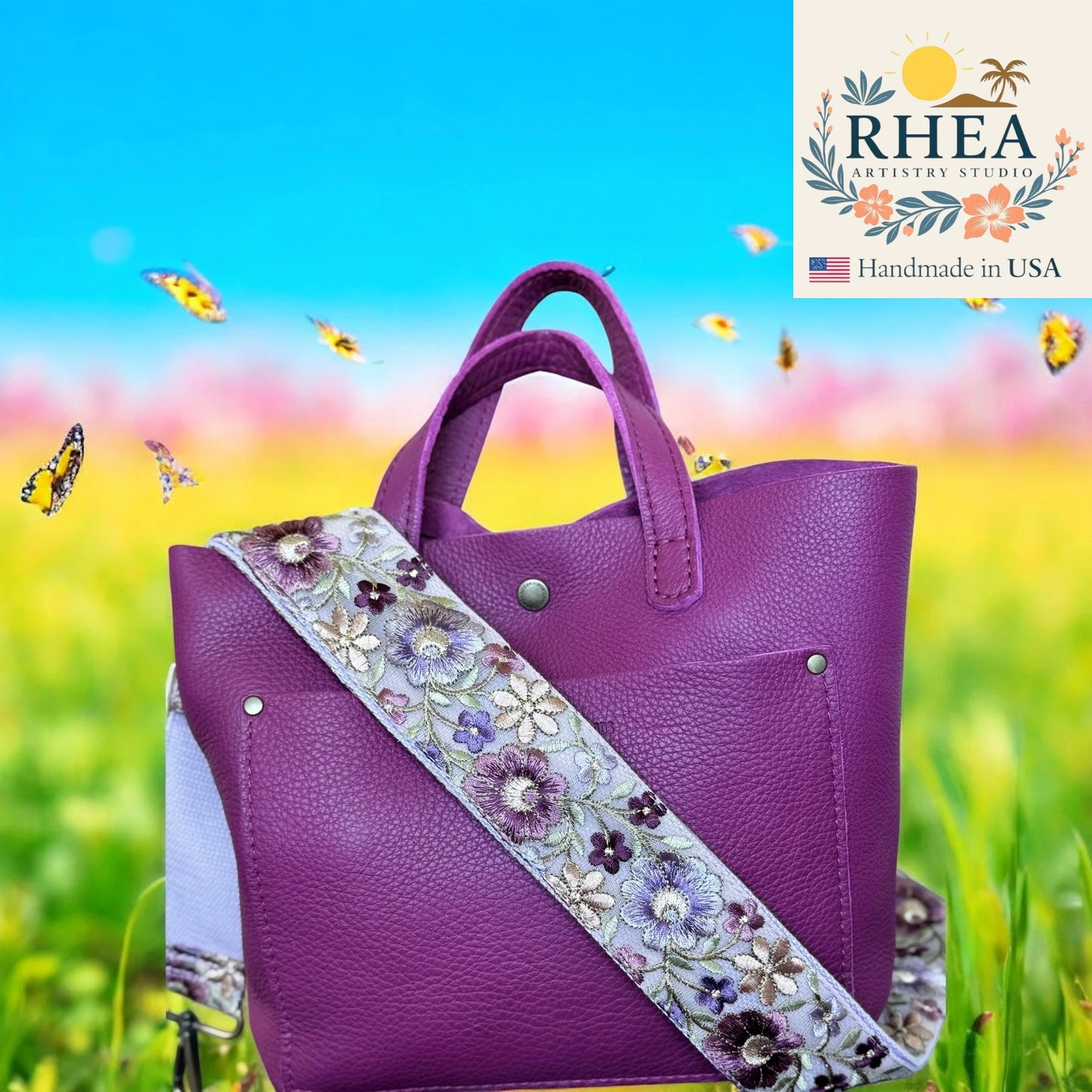 Purple handbag with floral purse strap on a colorful background, featuring the Rhea Artistry Studio logo.
