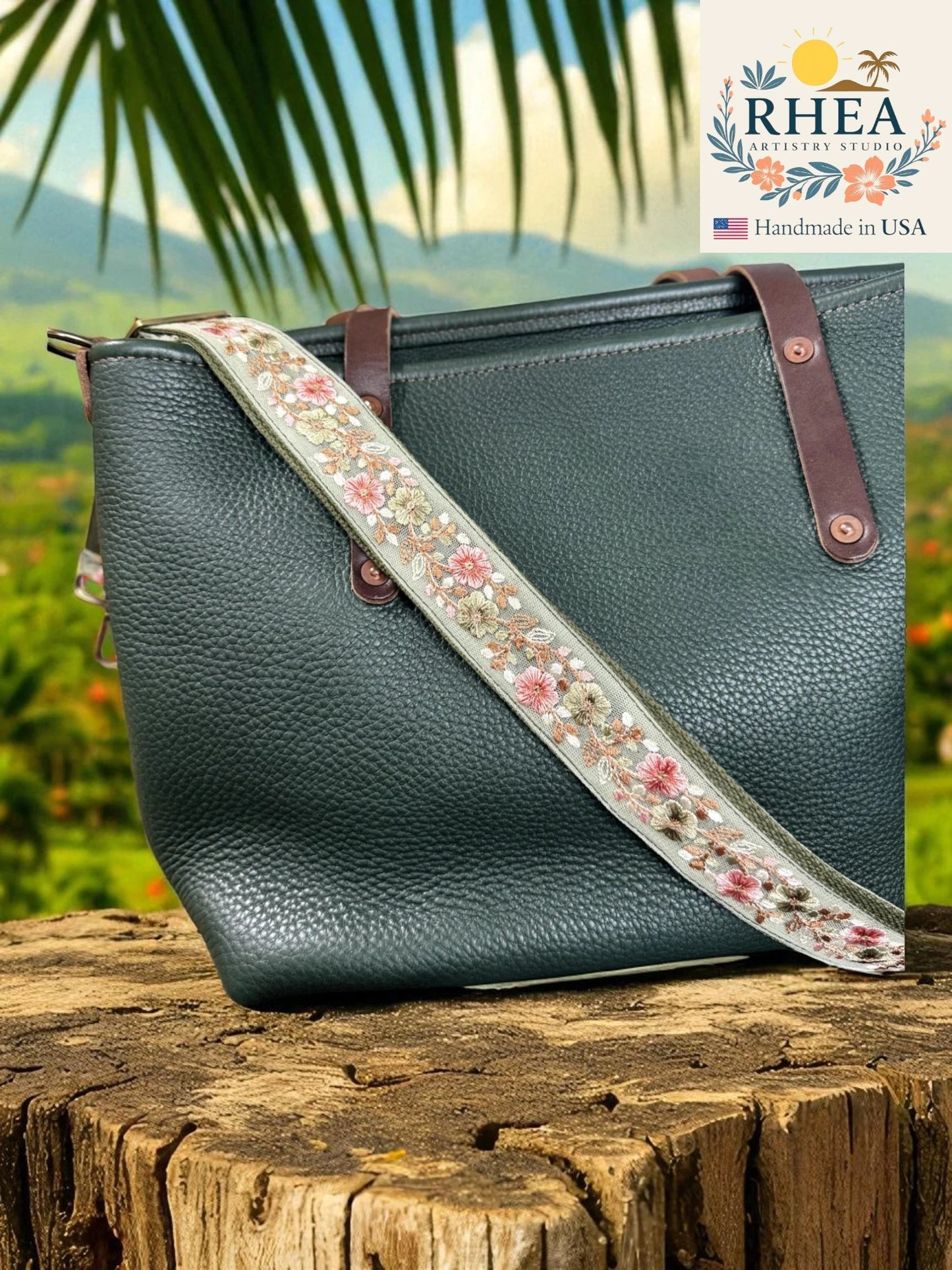Green handbag with floral bag strap on a wooden surface, with 'RHEA' branding in the corner.