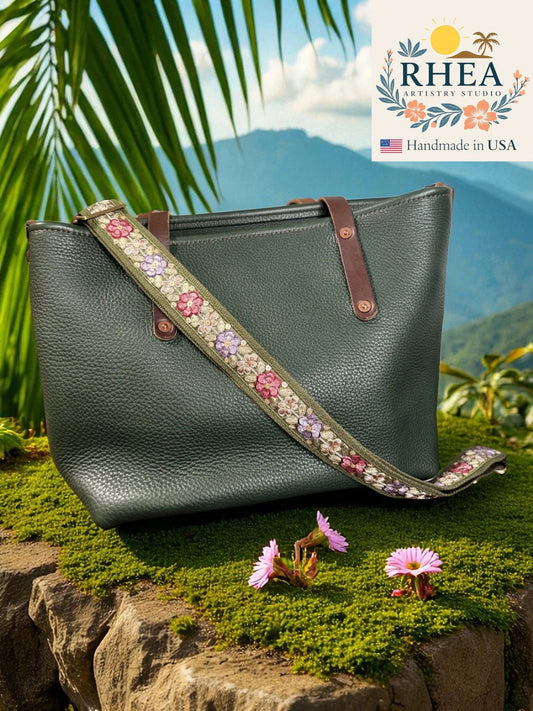Green handbag with floral strap on a natural background, featuring RHEEA branding.