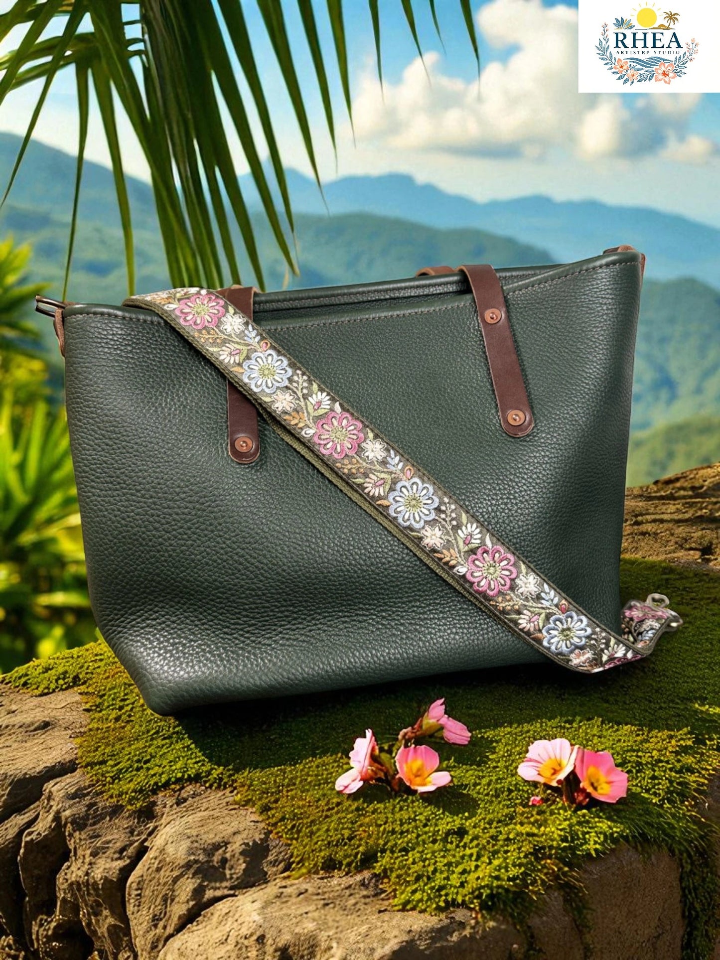 Green leather handbag with floral strap on a rock with a mountainous background