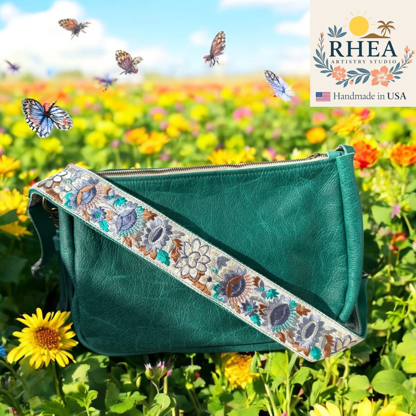 Green handbag with floral purse strap in a field of flowers and butterflies, featuring RHEEA Artistry Studio branding.