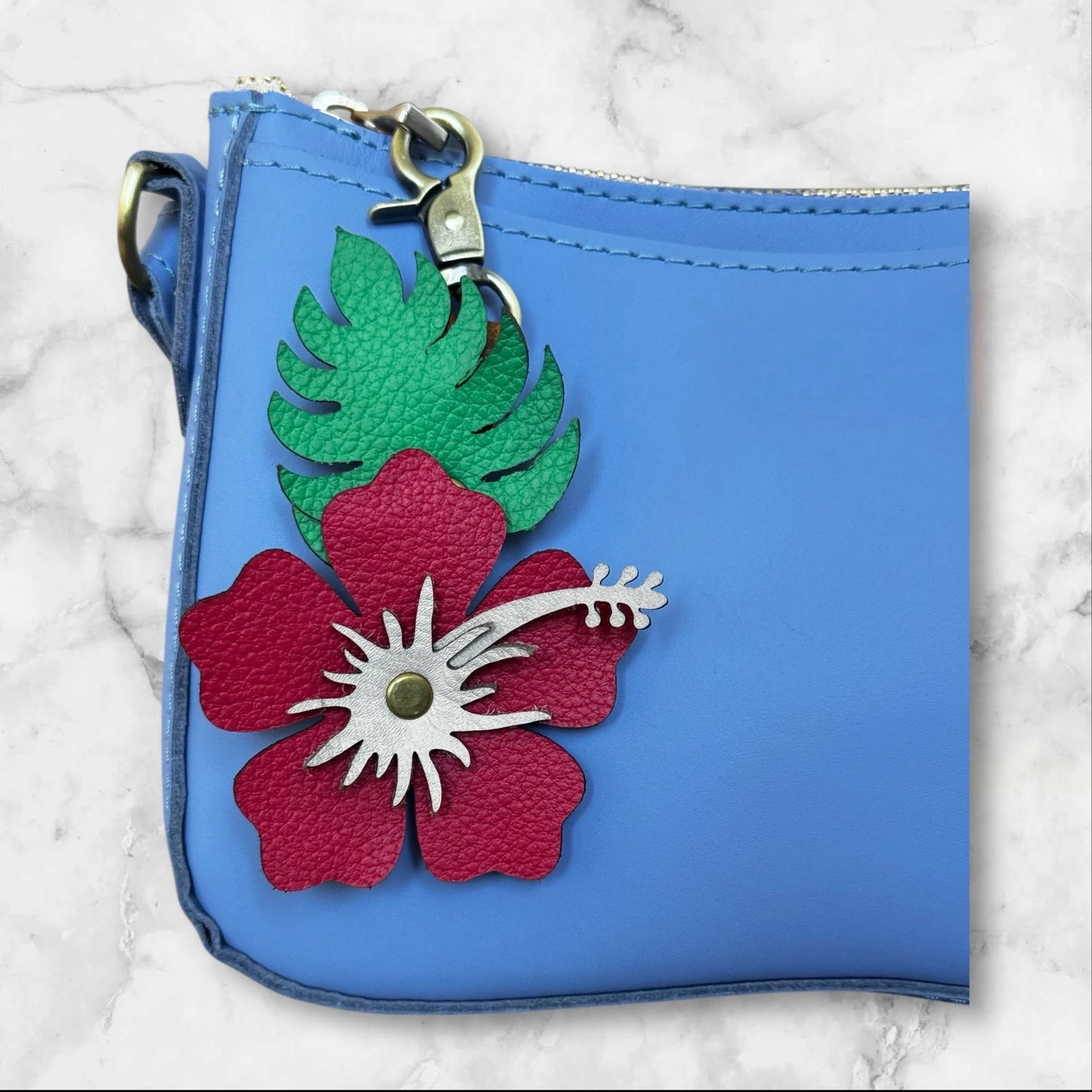 Red with blush stamen leather hibiscus flower on a blue bag for tropical vibe - close up