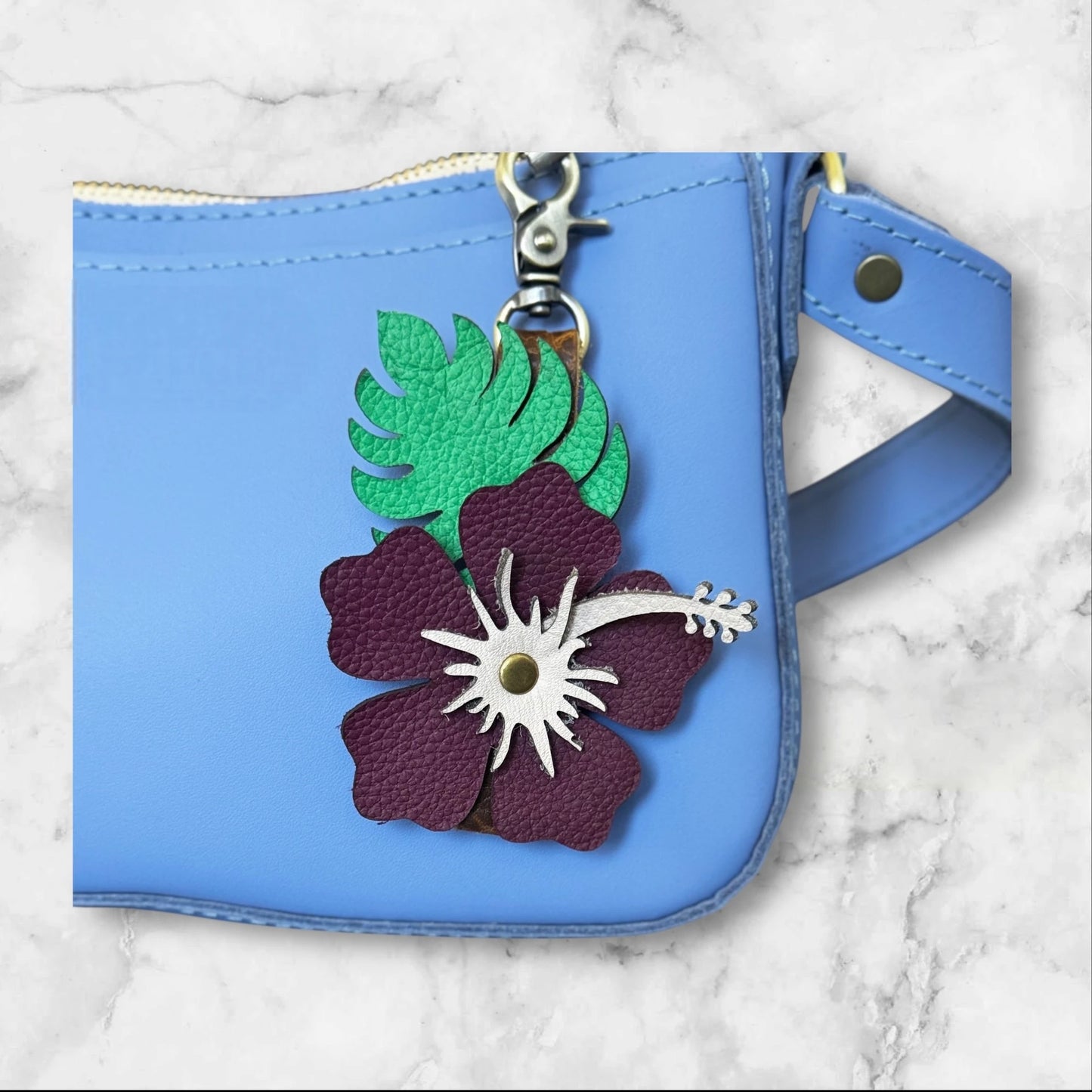 Plum with blush stamen hibiscus leather flower with green monstera leaf for a tropical vibe on a blue bag