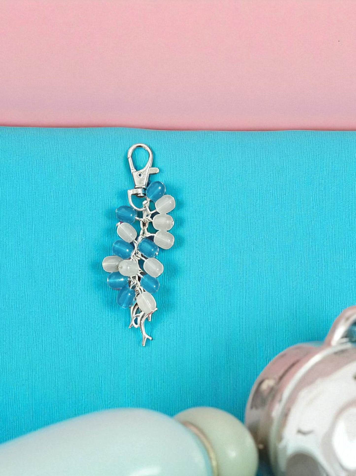 Silver keychain with blue and white stones on a pink and blue background