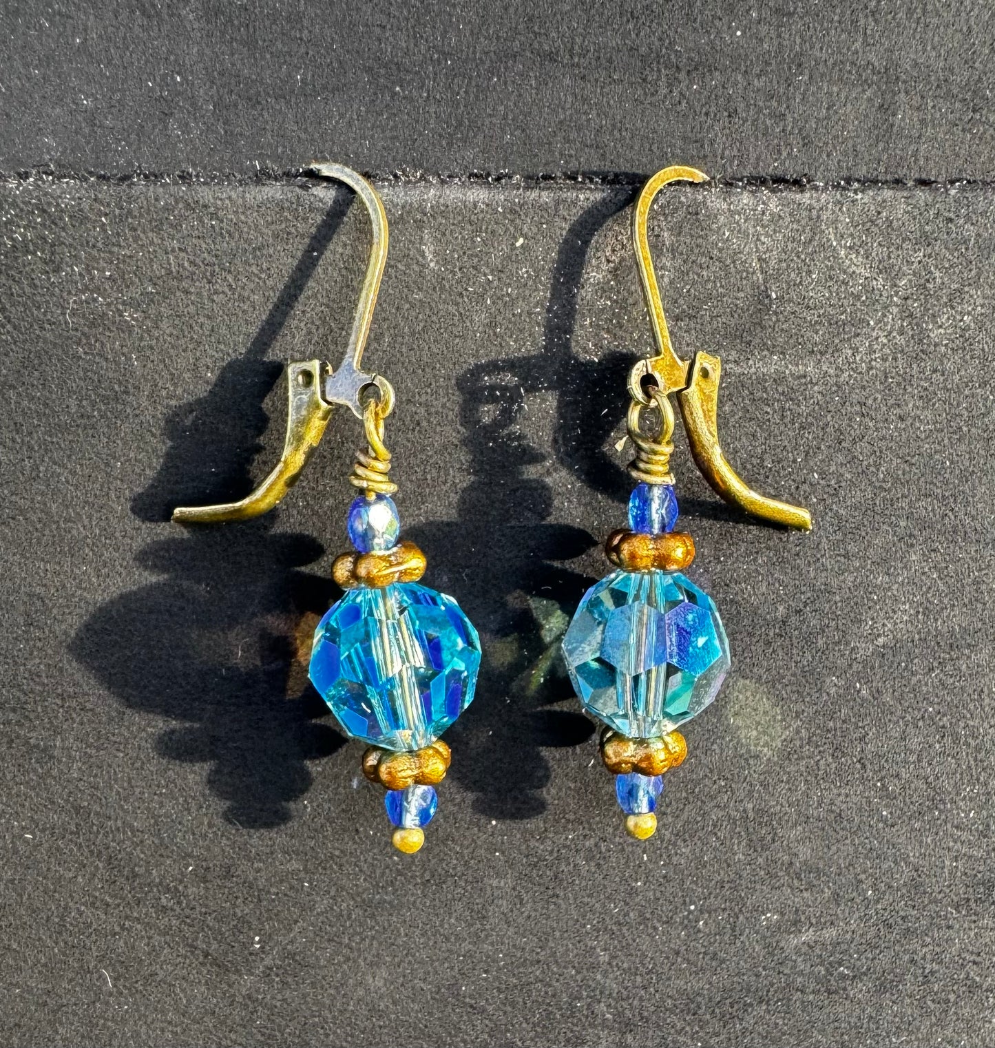 Gold and blue beaded earrings on a black bag