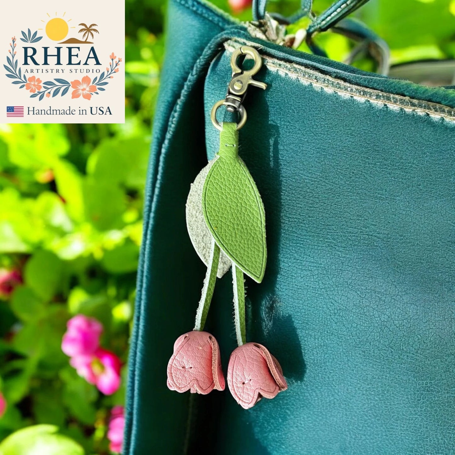 Green leather bag with pink tulip leather purse charm against a blurred green background