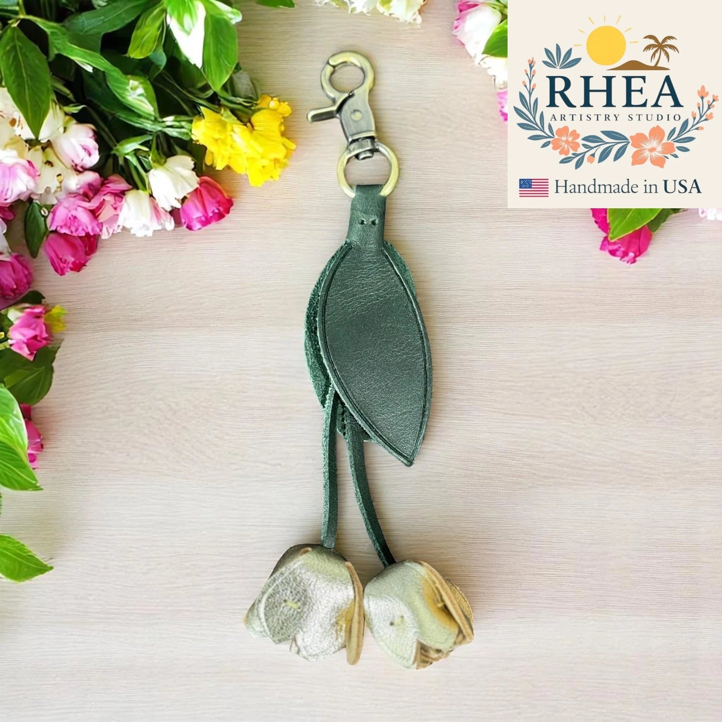 Green floral leather purse charm with flowers in the background and RHEA Artistry Studio logo.