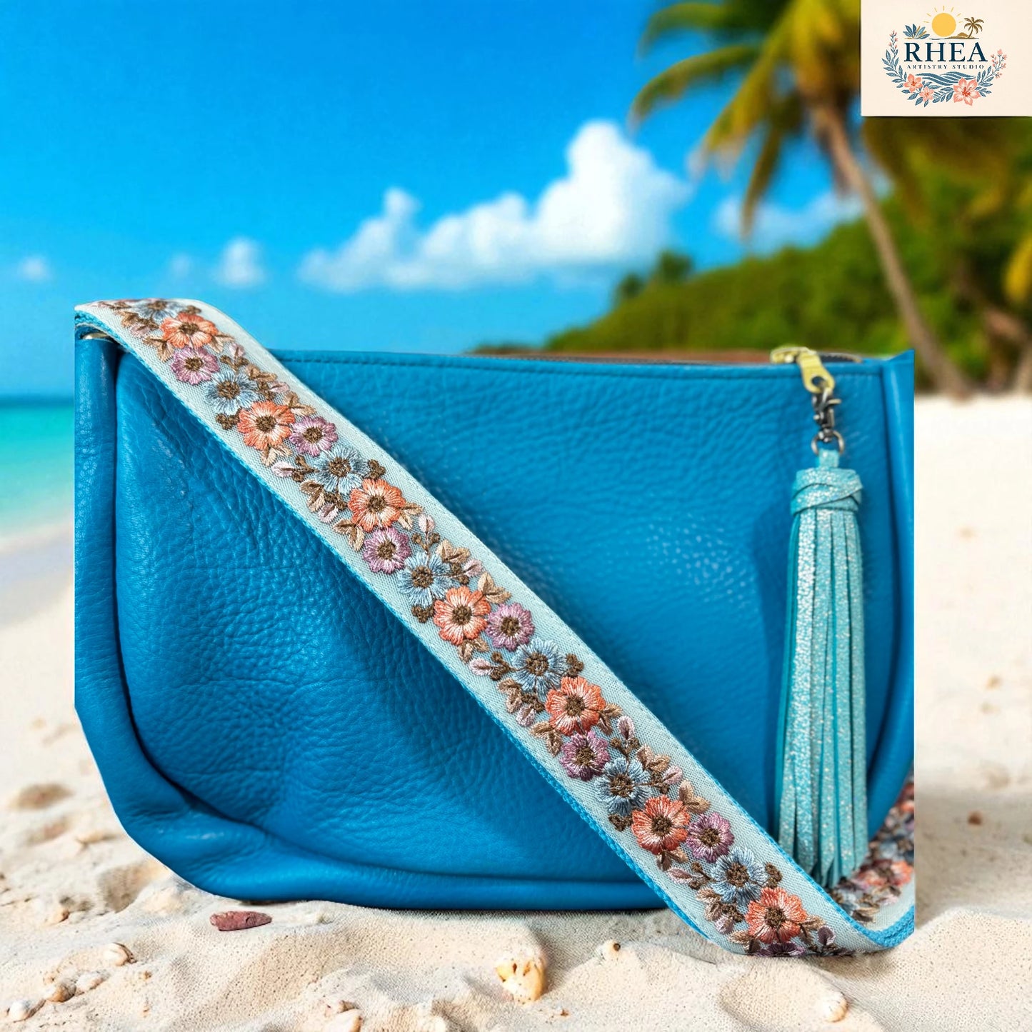 Blue handbag with floral strap and tassel on a beach with palm trees in the background