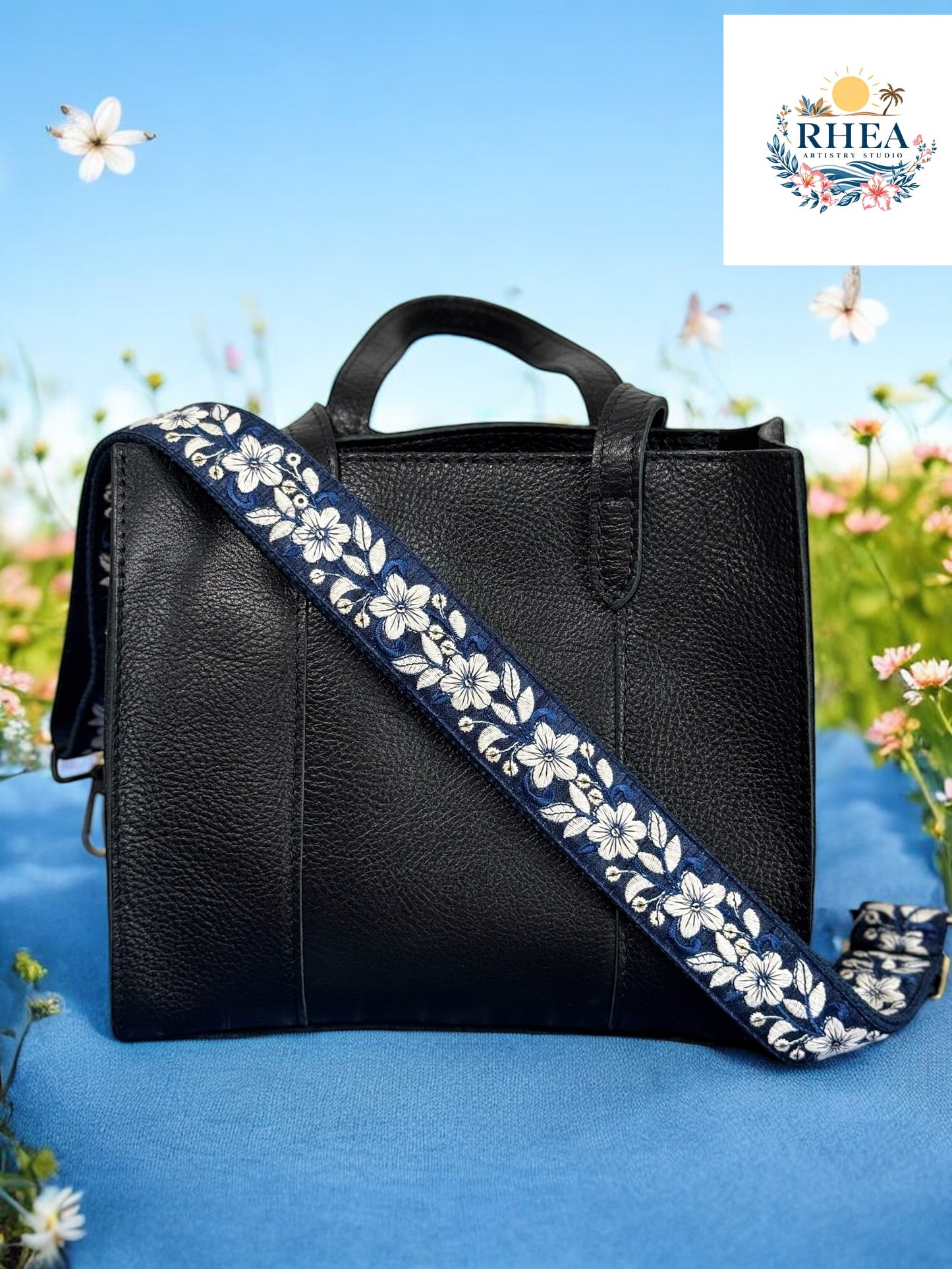 A black purse with a floral patterned strap, displayed against a blue background with floral motifs.