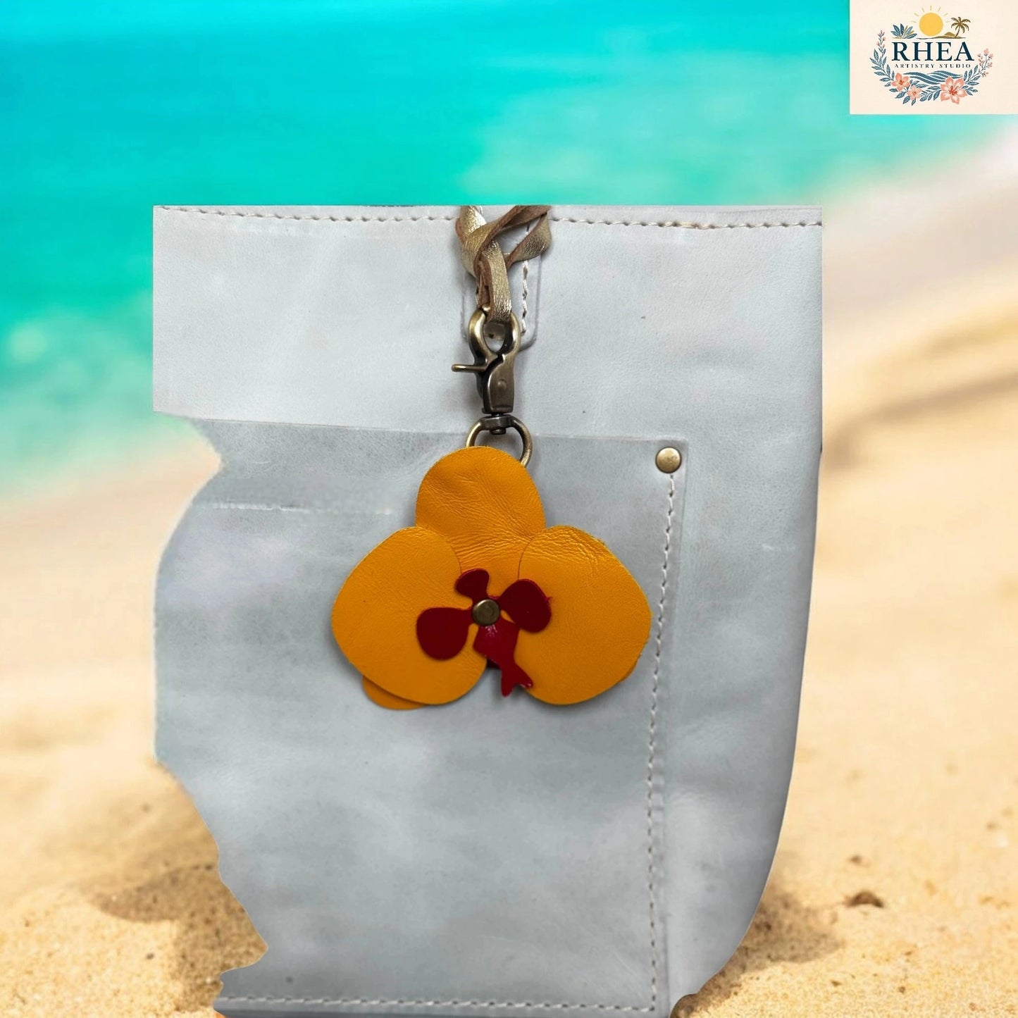 White pouch with a yellow flower keychain on a beach background