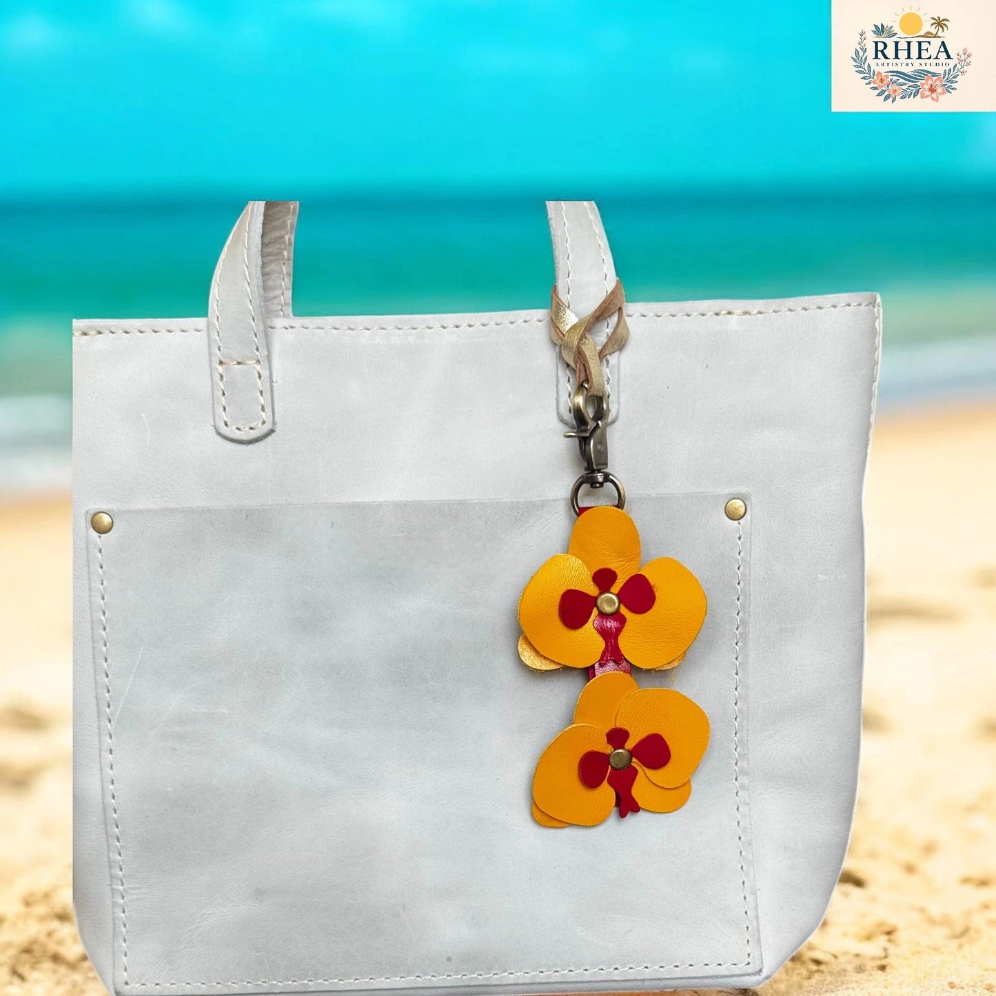 White tote bag with a floral keychain on a beach background