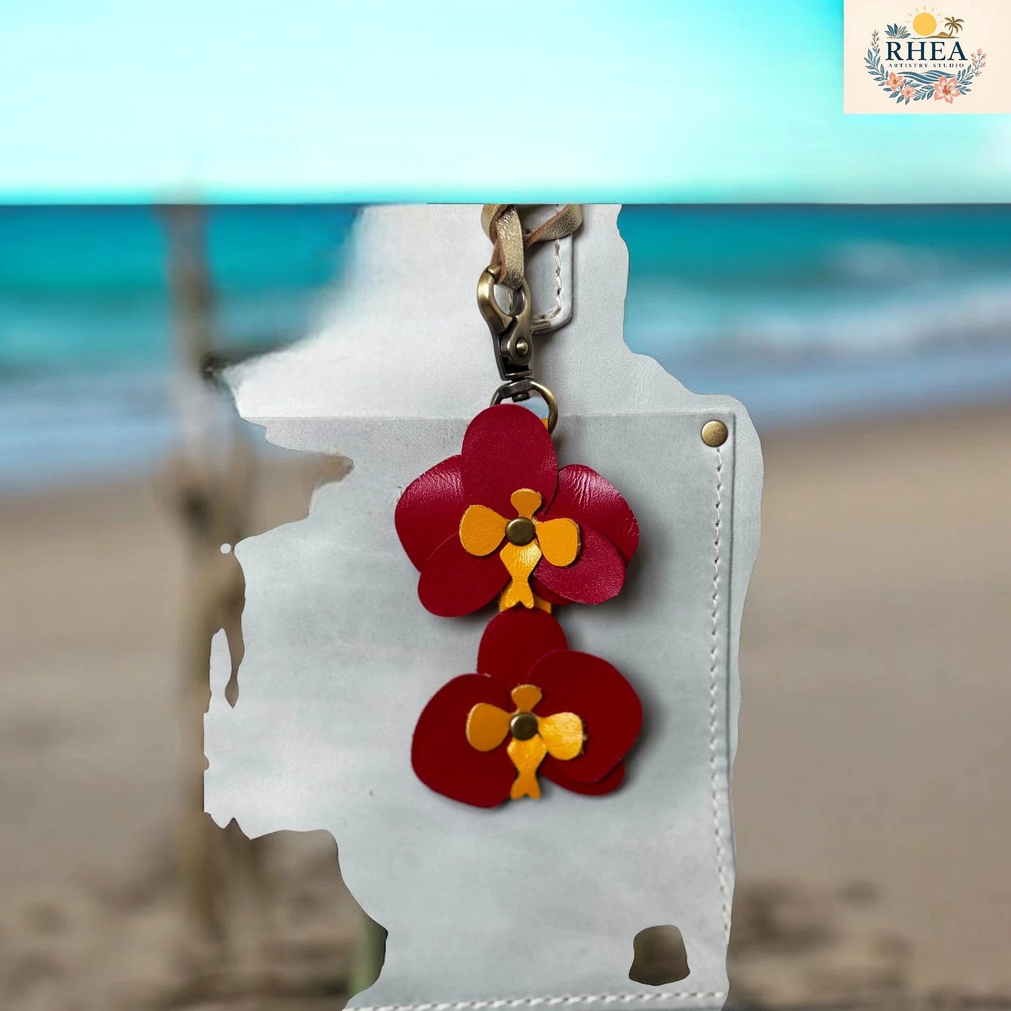 White phone case with red floral designs on a blurred beach background
