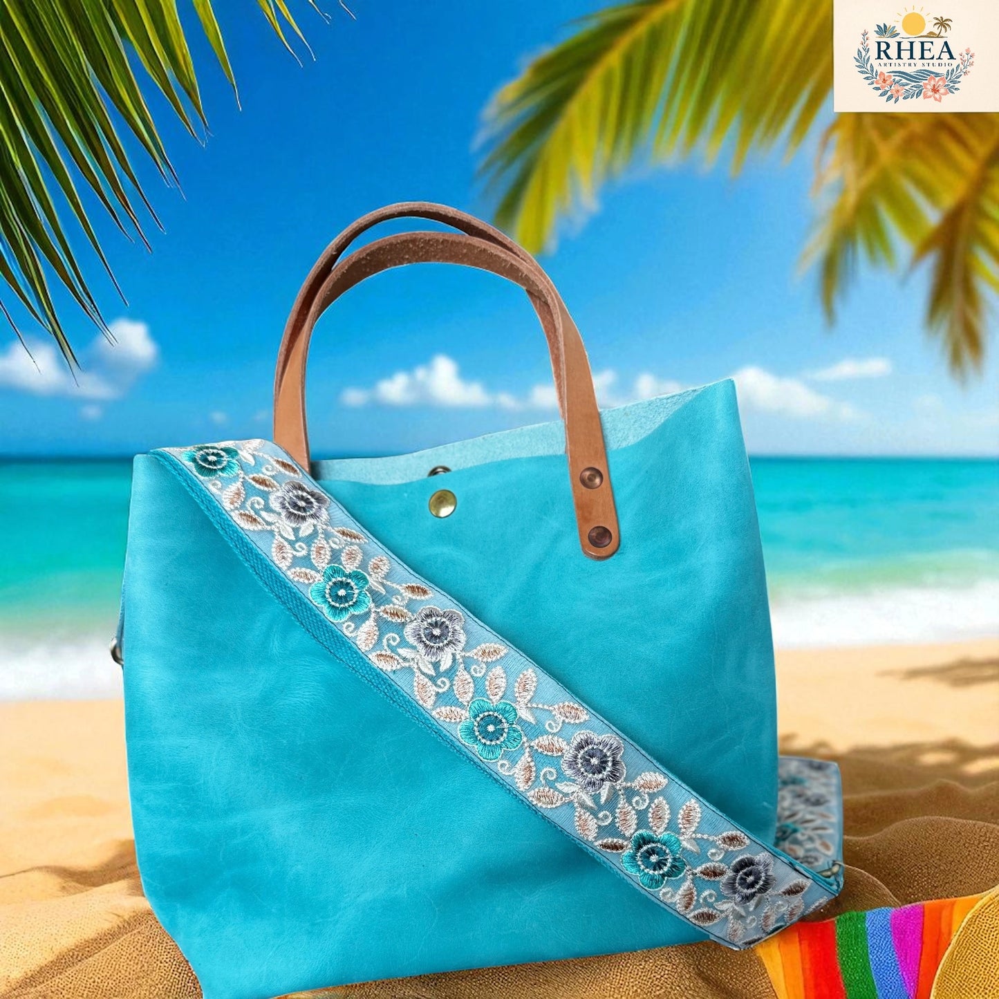Blue tote bag with floral strap on a beach with palm trees and blue sky.