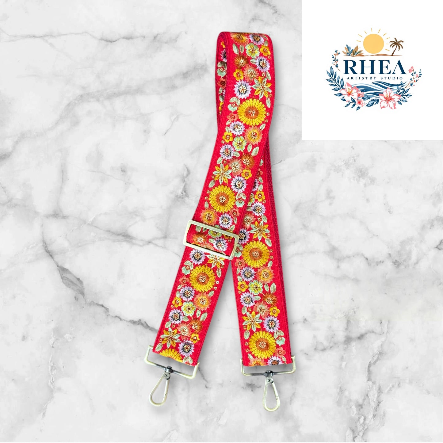 A floral embroidered purse strap in multicolor, attached to a black leather bag with brushed brass hardware.