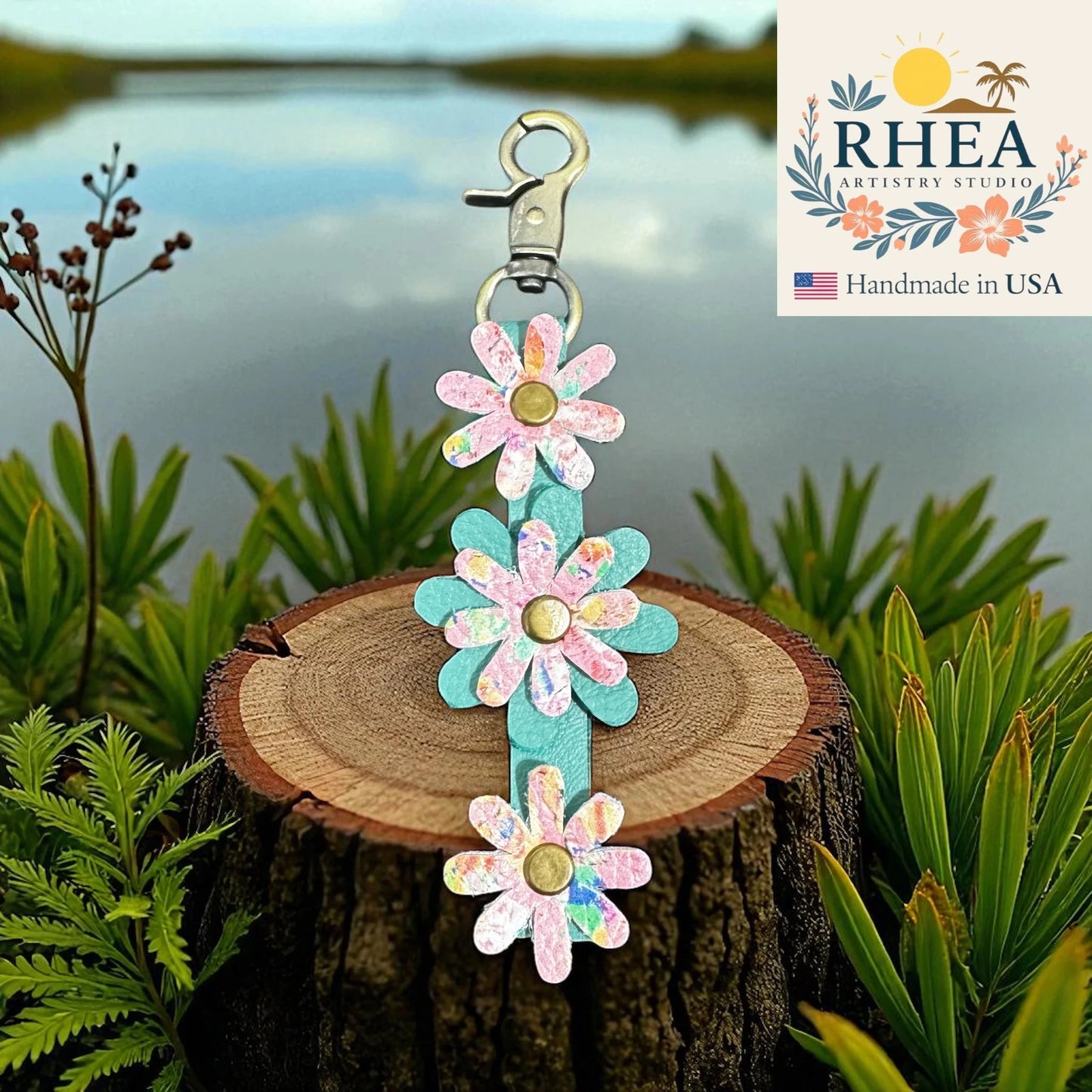 Floral leather purse charm on a wooden stump with RHEA Artistry Studio branding.