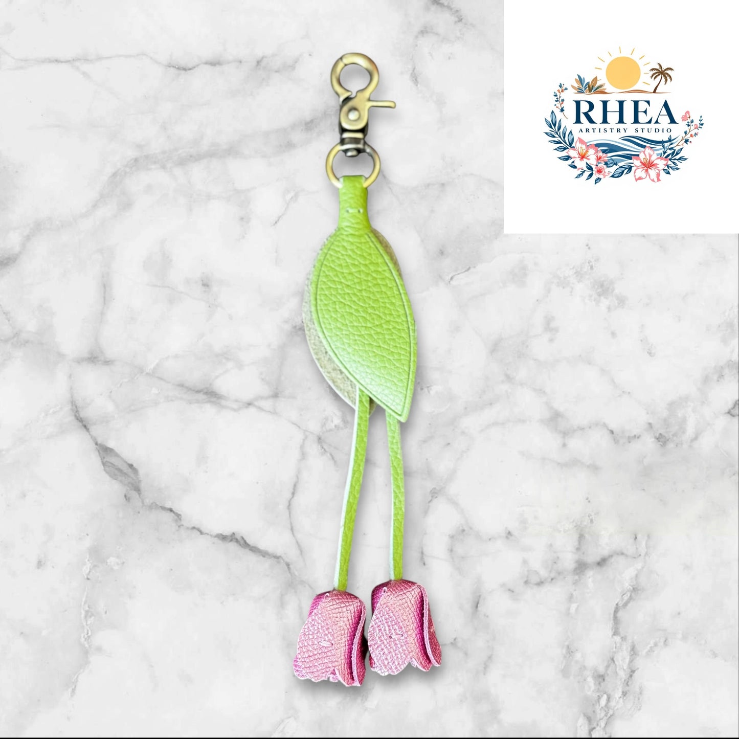 Green and purple keychain on a white surface with grass and flowers in the background