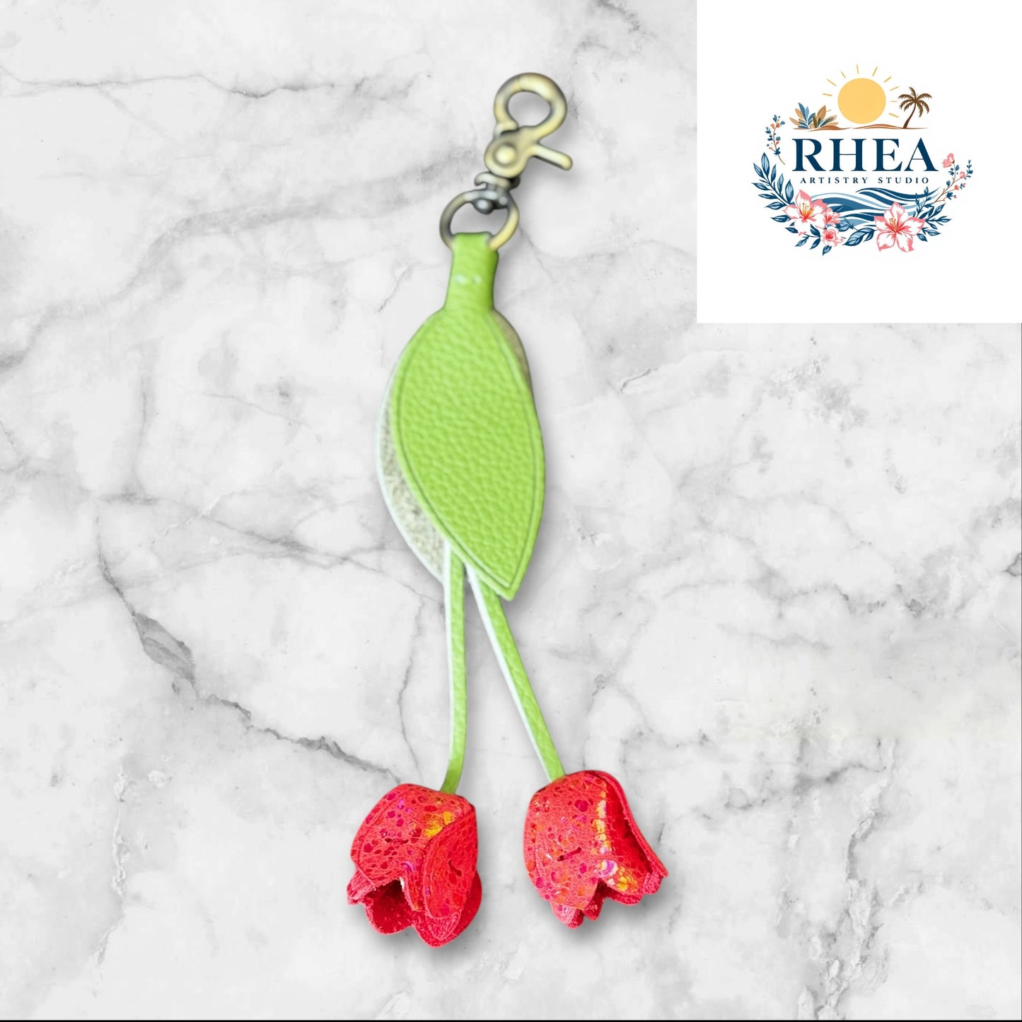 Green and red keychain on a white surface with grass and flowers in the background