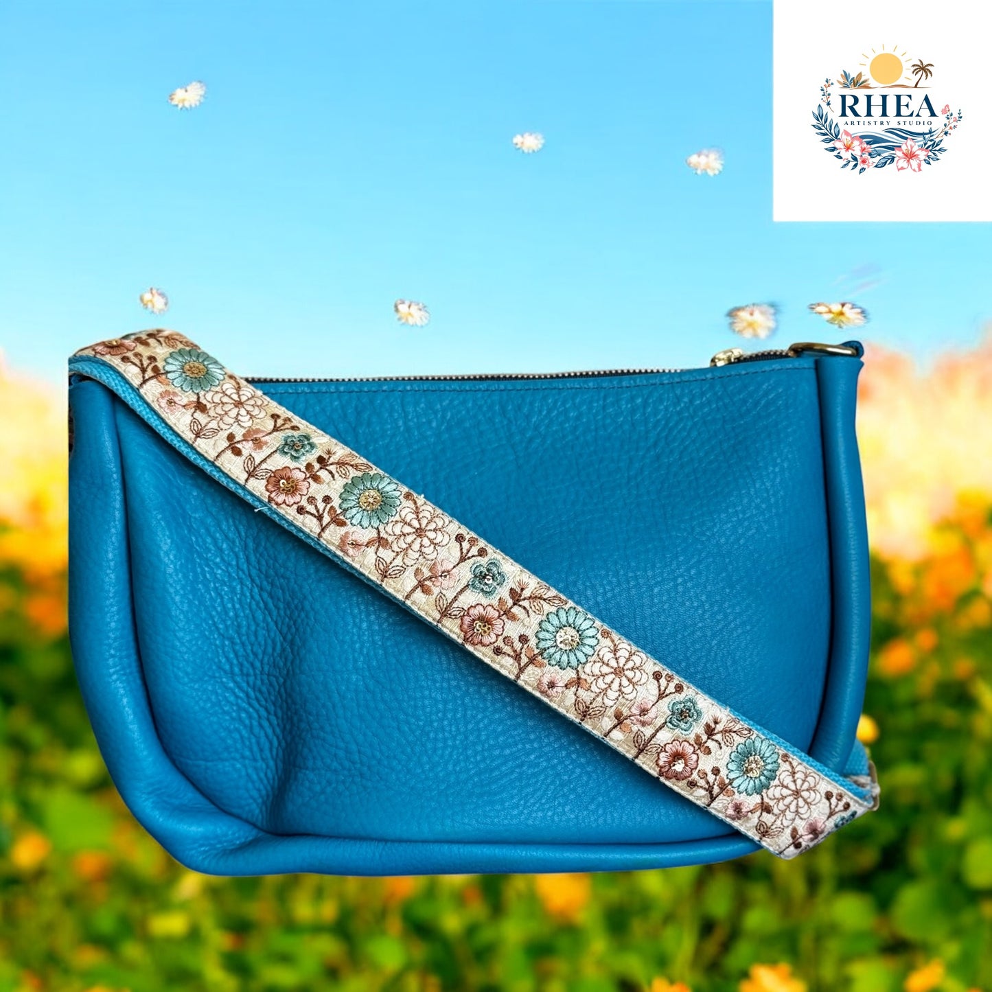 Blue handbag with floral strap against a blurred natural background