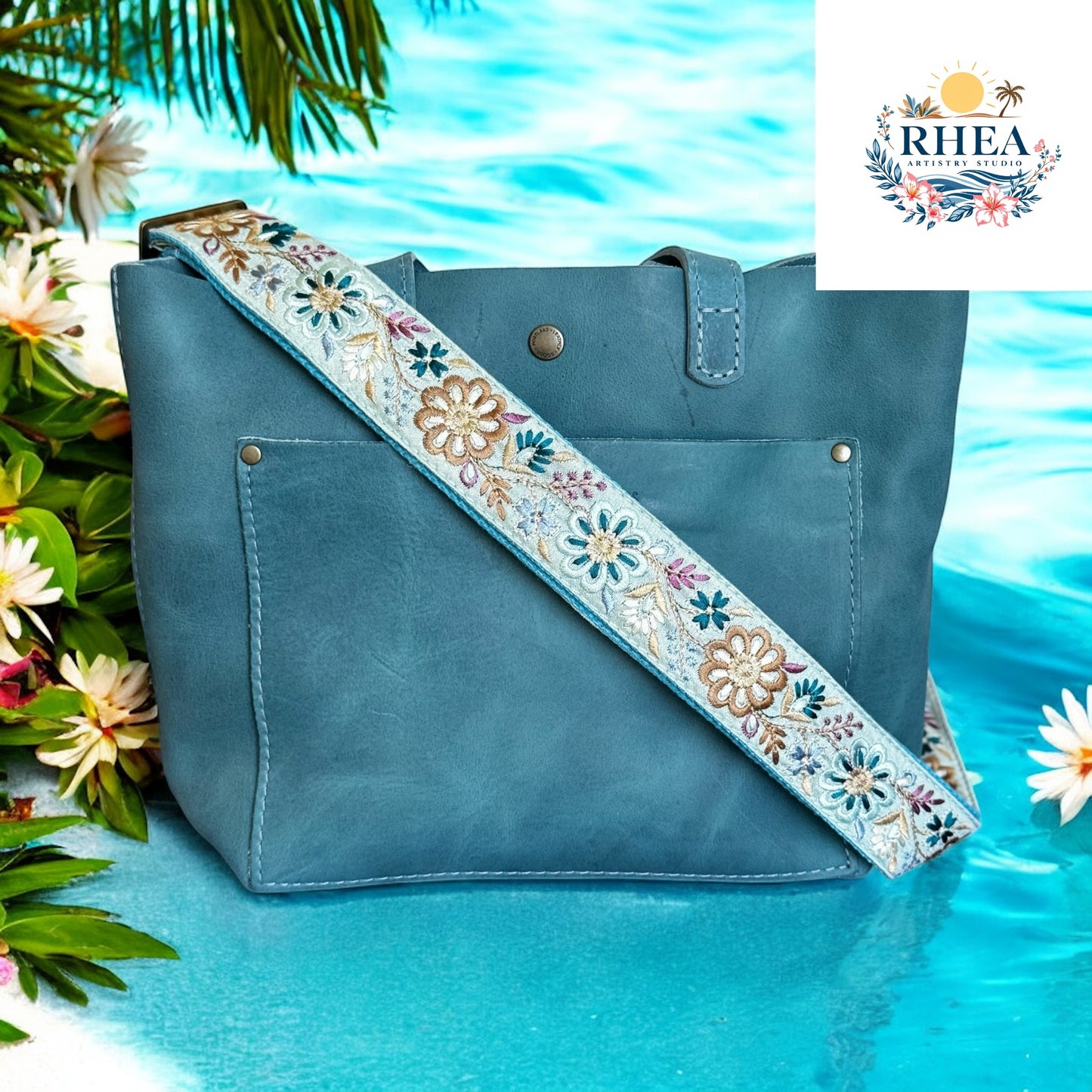 This vibrant aqua floral strap features intricately embroidered blossoms in shades of teal, cream, and bronze. A perfect replacement or upgrade for your favorite bag, it brings a fresh pop of color and artisan charm.