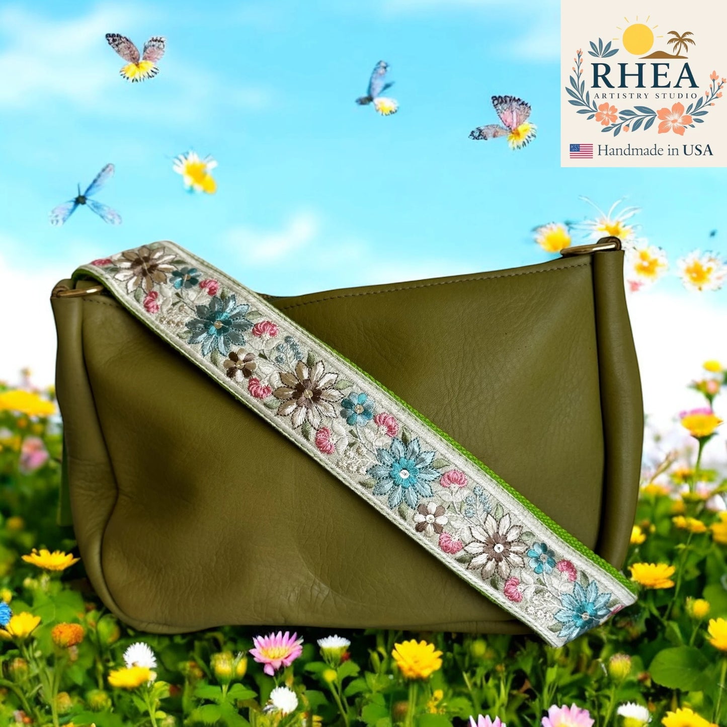Green handbag with floral purse strap in a field of flowers and butterflies, featuring RHEA Artisan Studio logo.
