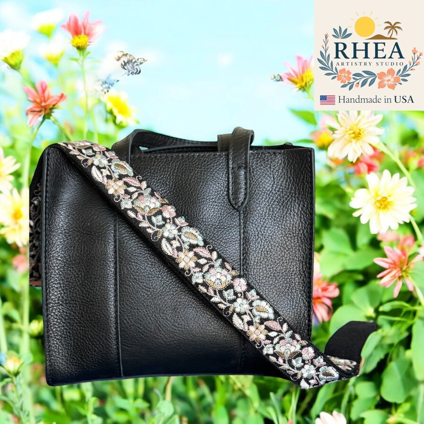 Black handbag with floral purse strap against a floral background, featuring the RHEA brand.
