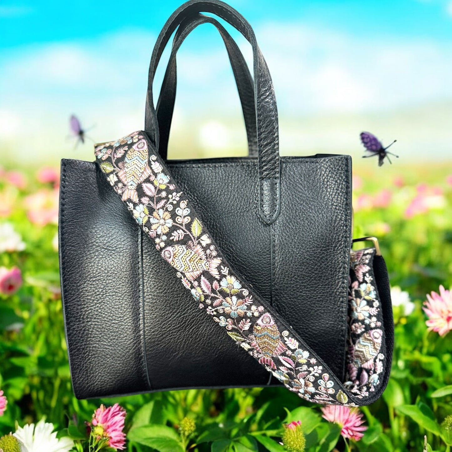 Adjustable embroidered purse strap with floral patterns and gold hardware, displayed on a gray background.