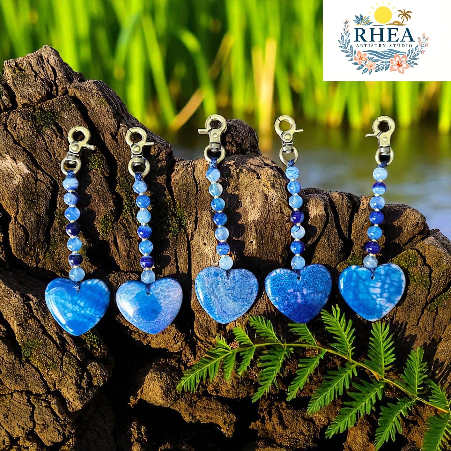 Blue heart-shaped keychains with beaded charms on a wooden log with a natural background