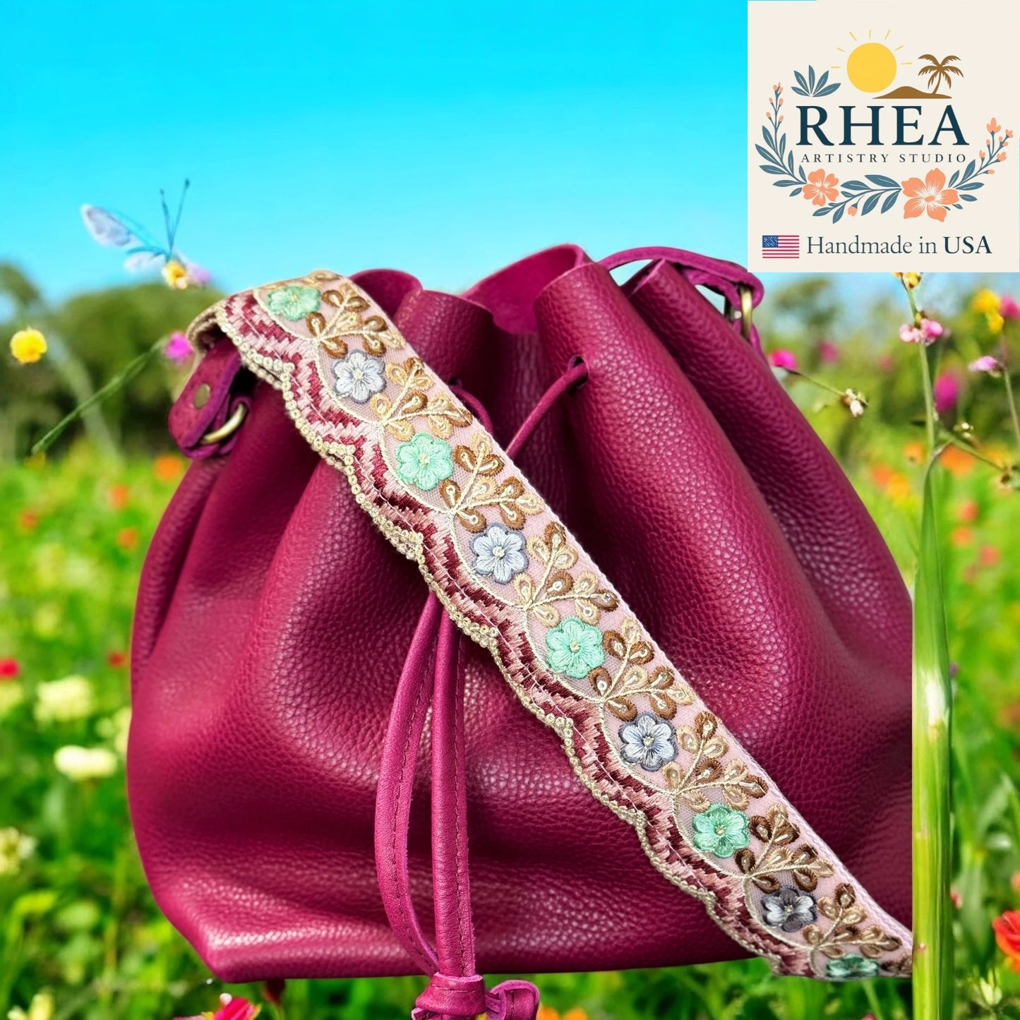 Pink leather bag with floral strap against a natural background, featuring the Rhea Artistry Studio logo.