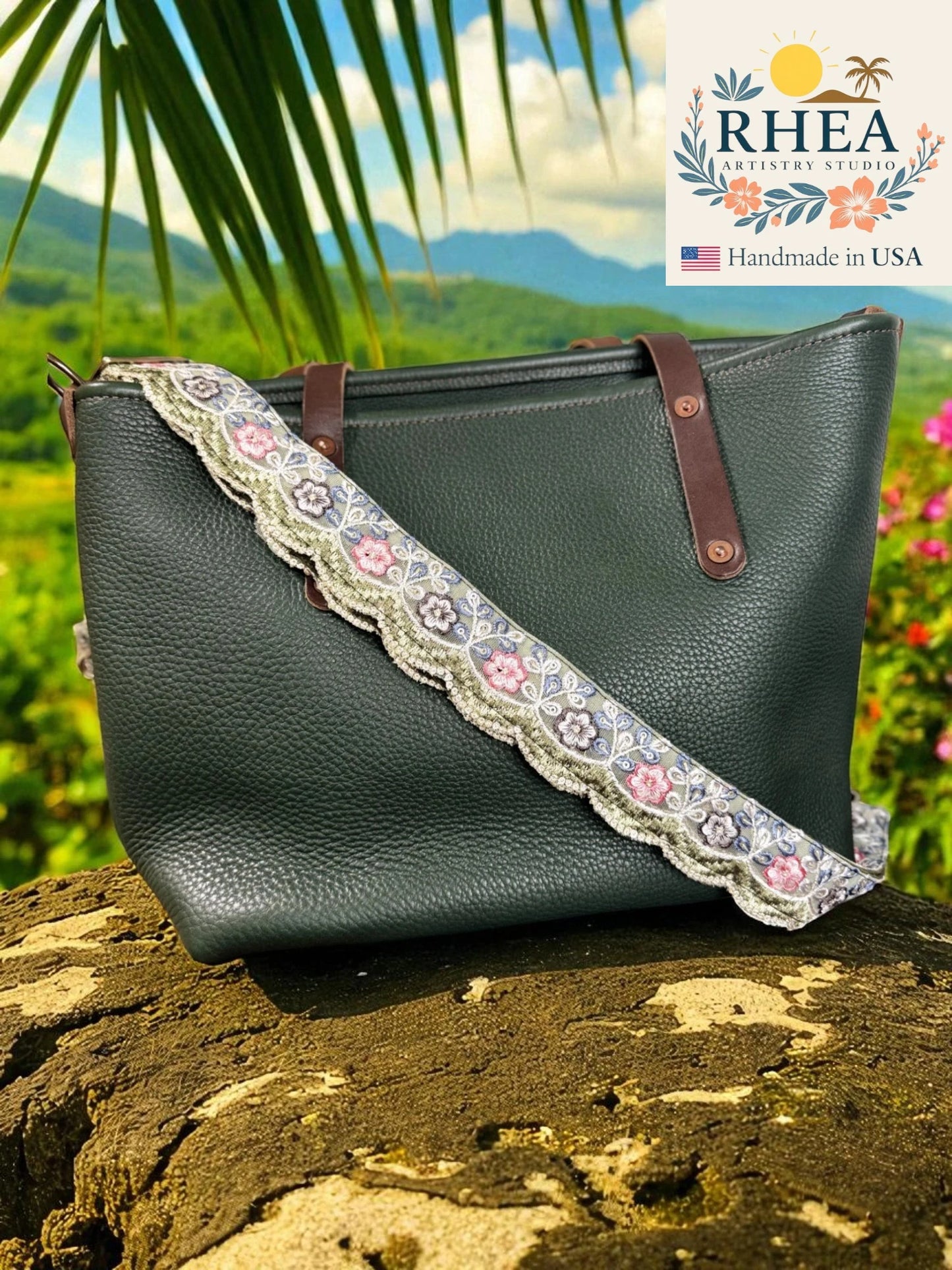 Green handbag with floral lace strap on a rock with a scenic background, featuring the RHEA Artisan Studio logo.