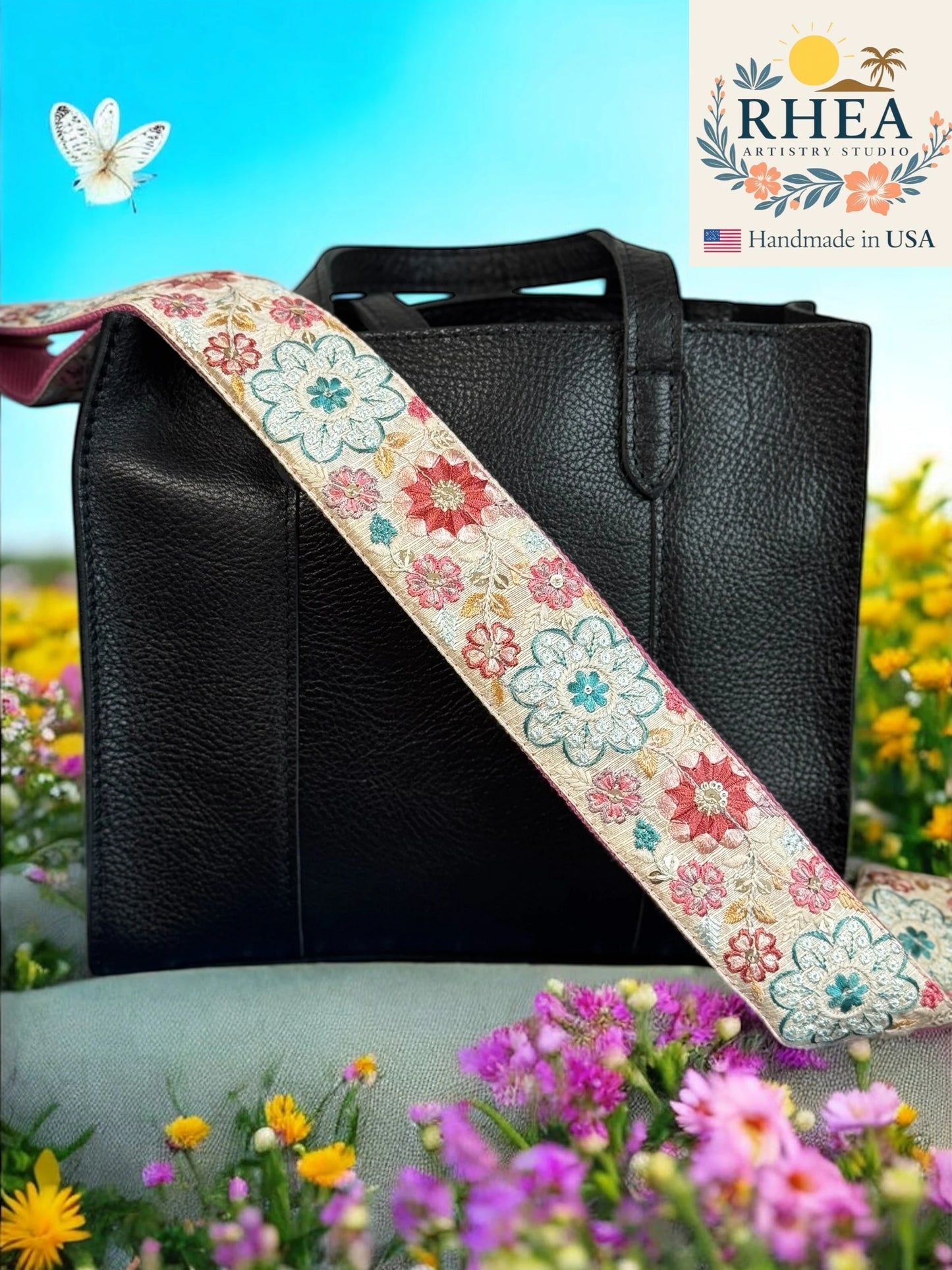 Black handbag with a floral purse strap against a natural background