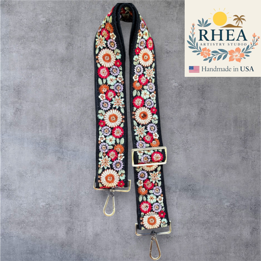 Floral patterned purse strap with RHEA Artistry Studio logo on a gray background