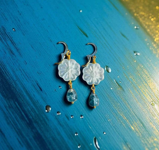 Floral earrings with blue beads on a textured blue and gold background